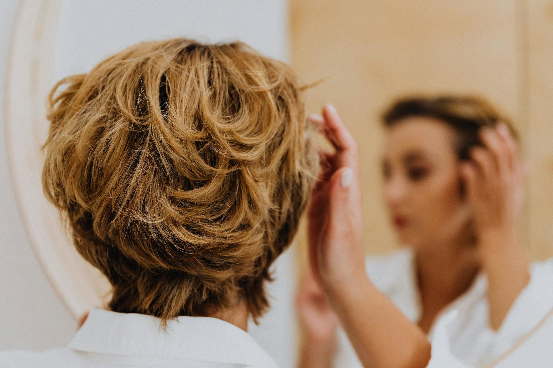 woman applying hair mousse blowout mirror