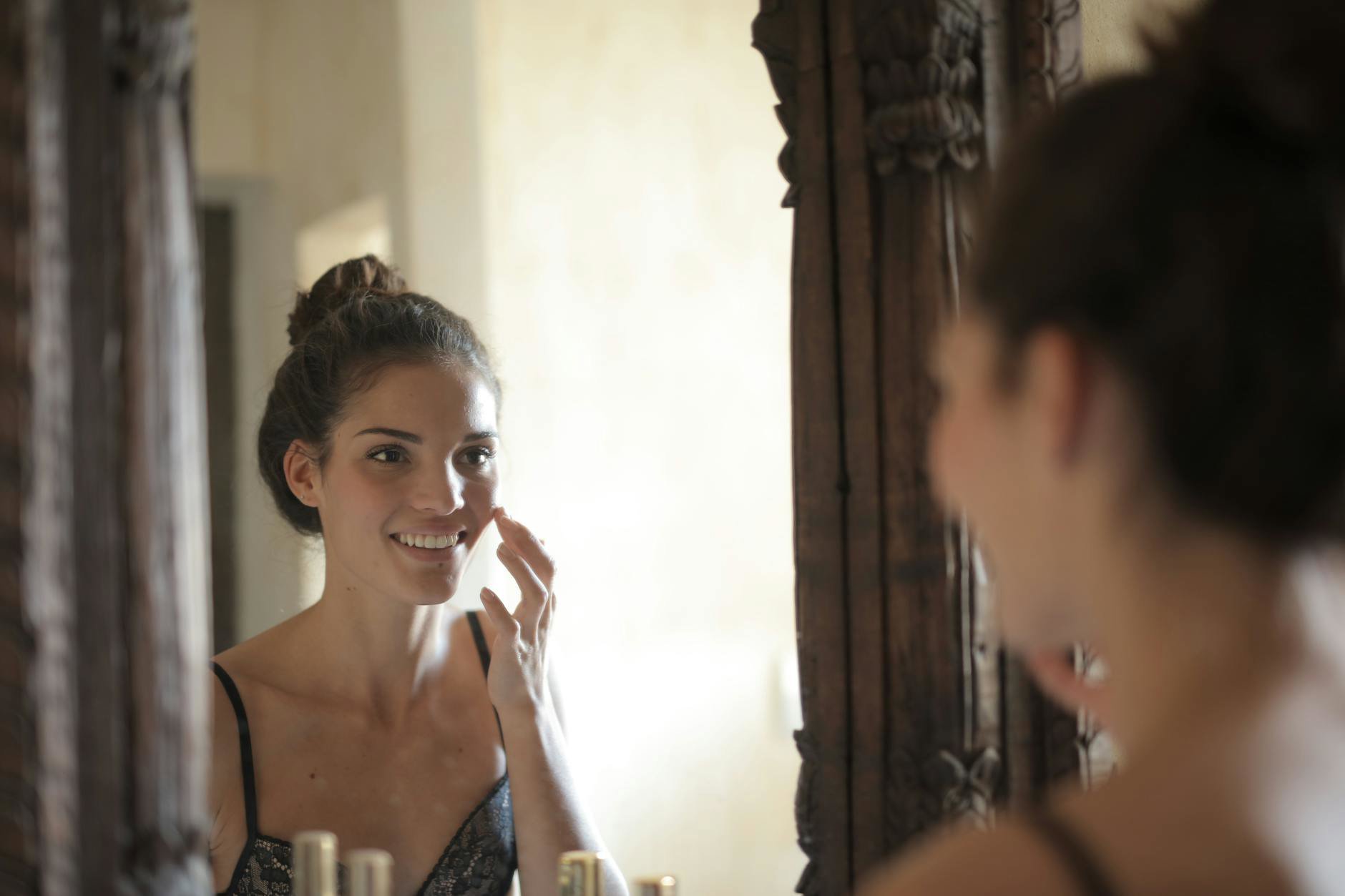 woman applying face primer mirror
