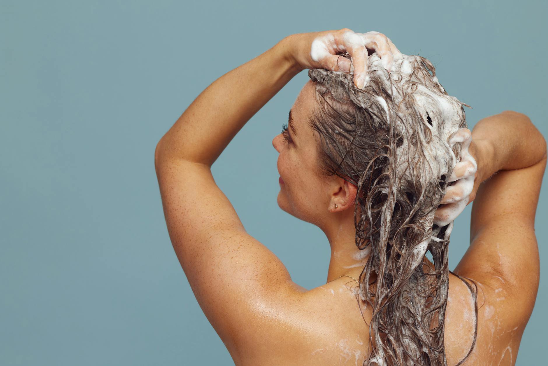 woman washing hair in shower with shampoo