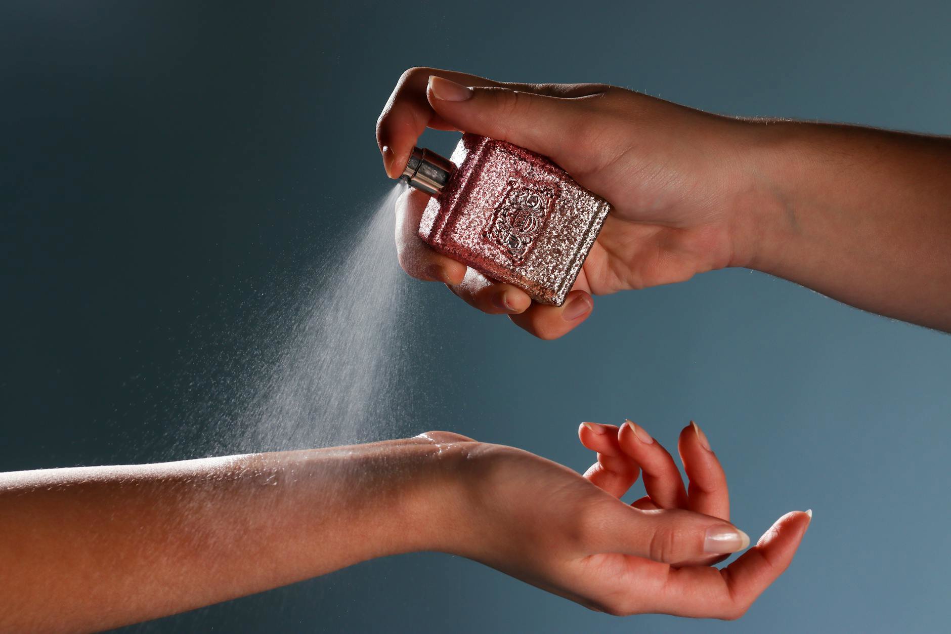 woman applying perfume on wrists close up