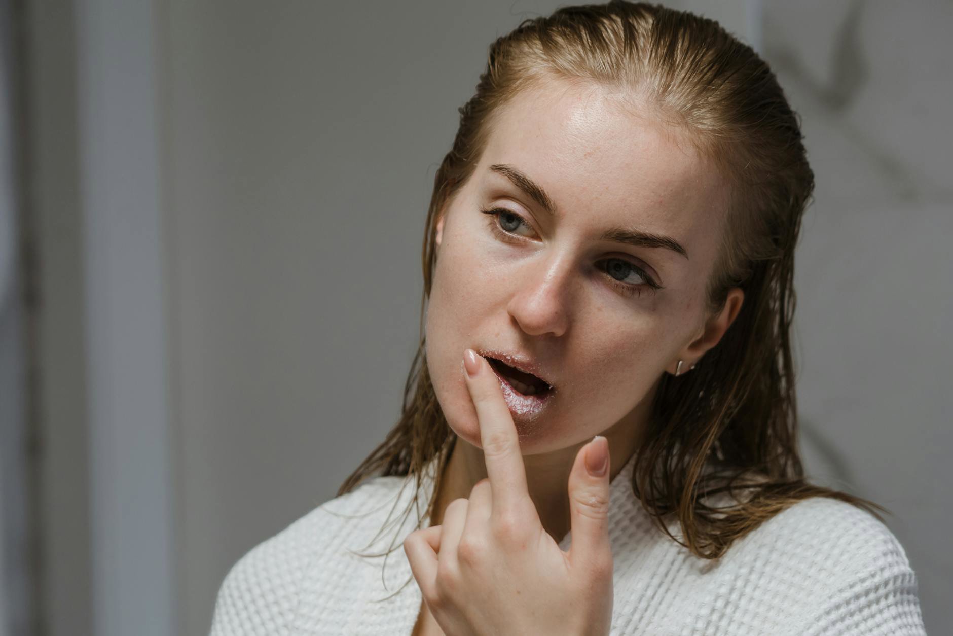 woman applying face oil on damp skin bathroom mirror