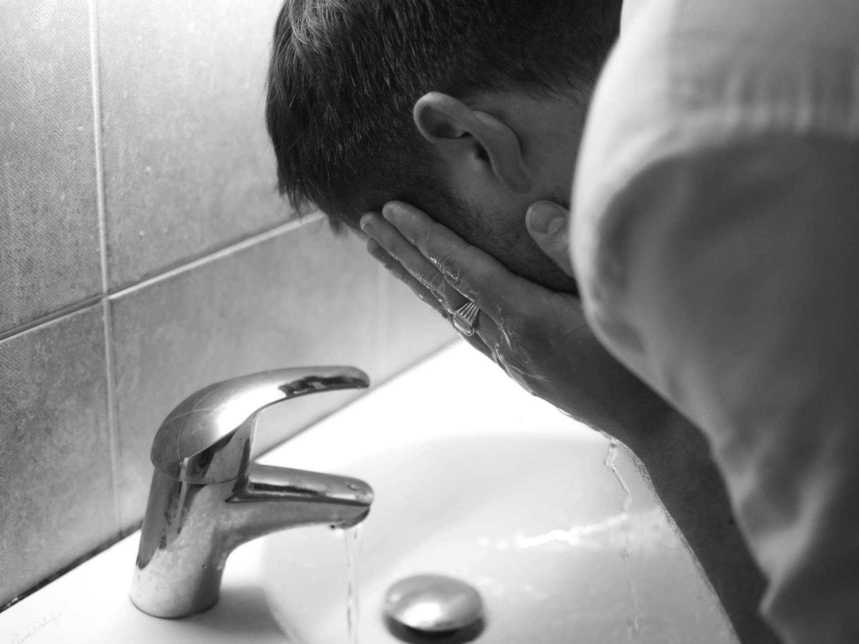 woman rinsing face with lukewarm water