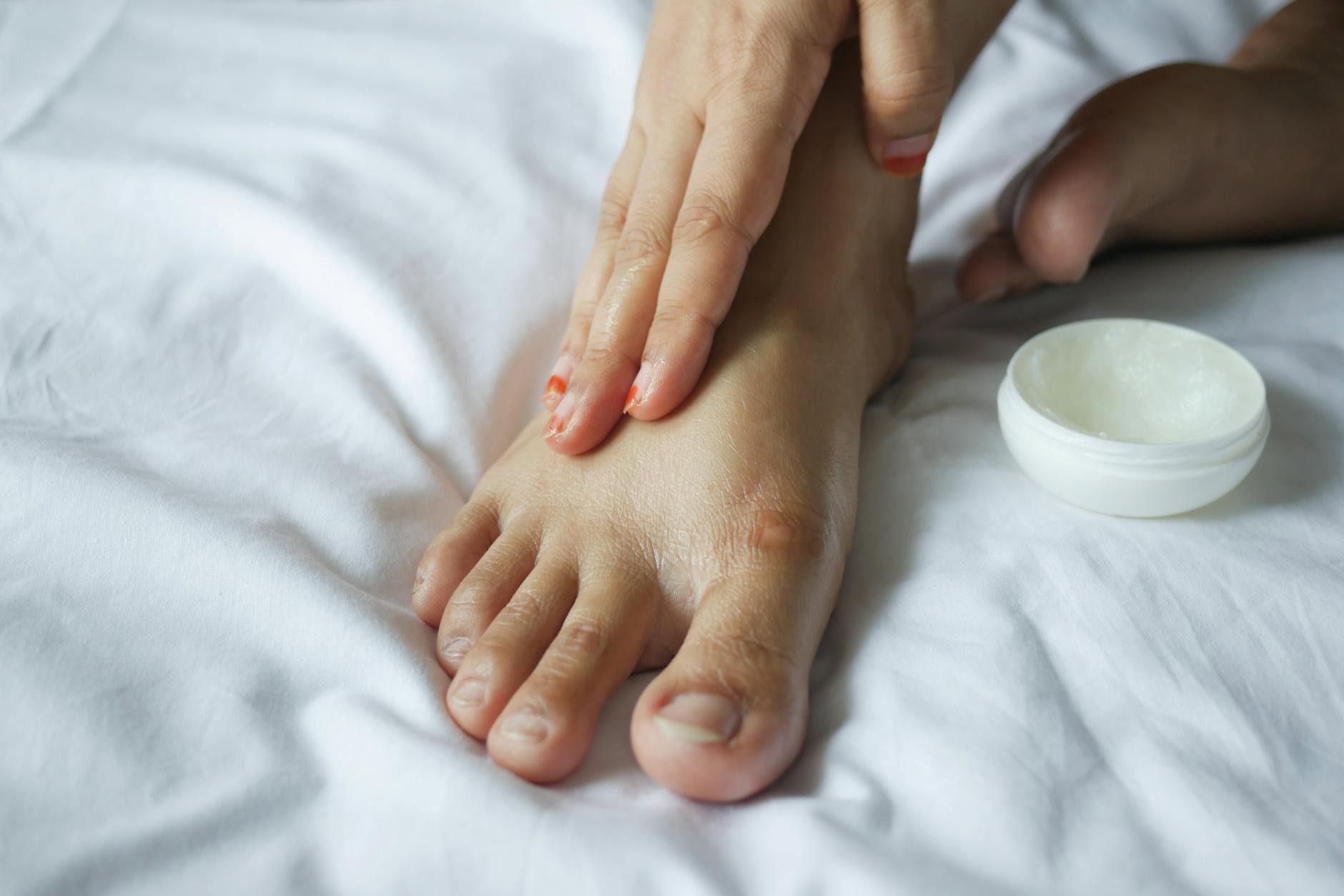 woman applying foot cream cotton socks at home