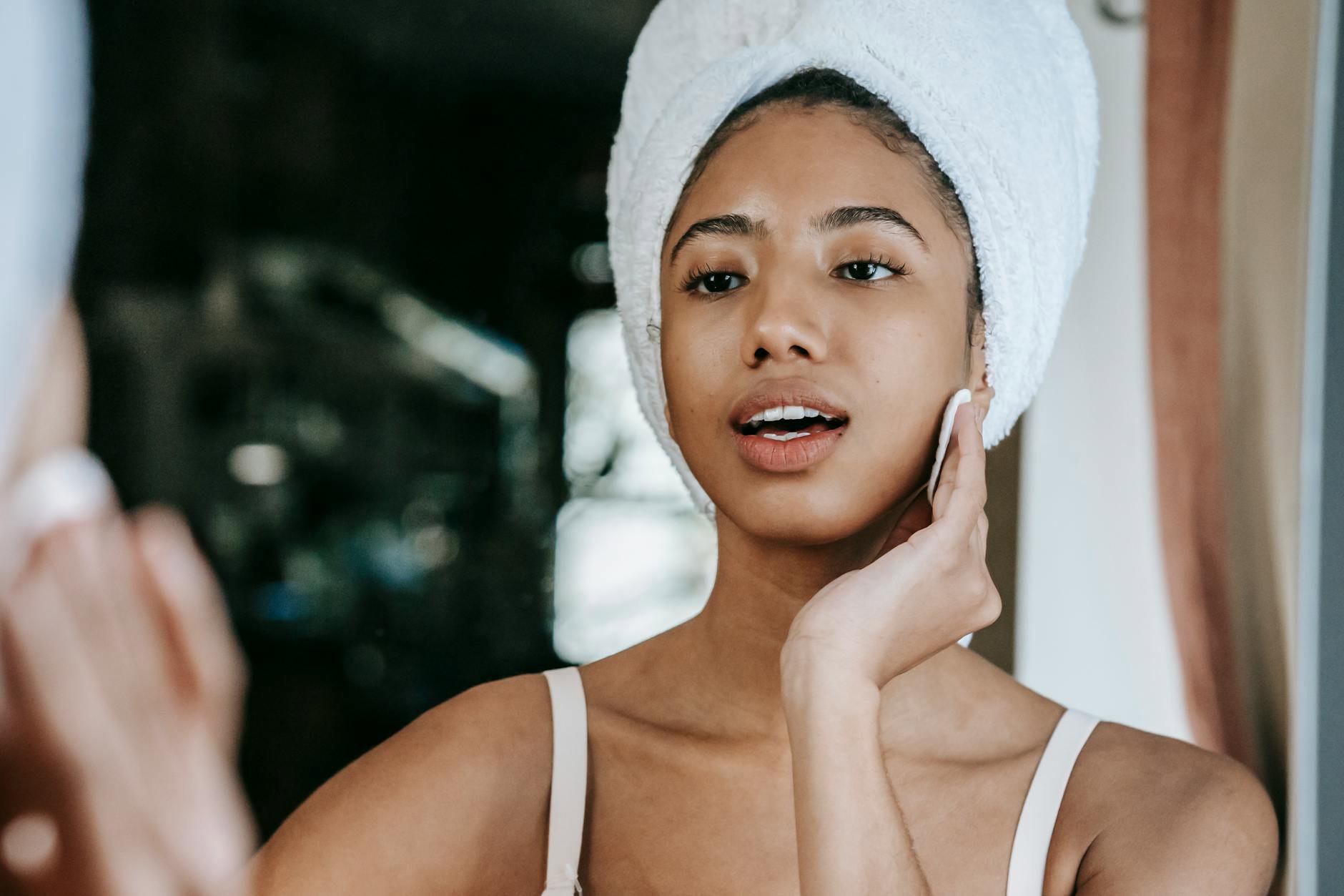 woman applying face toner cotton pad mirror