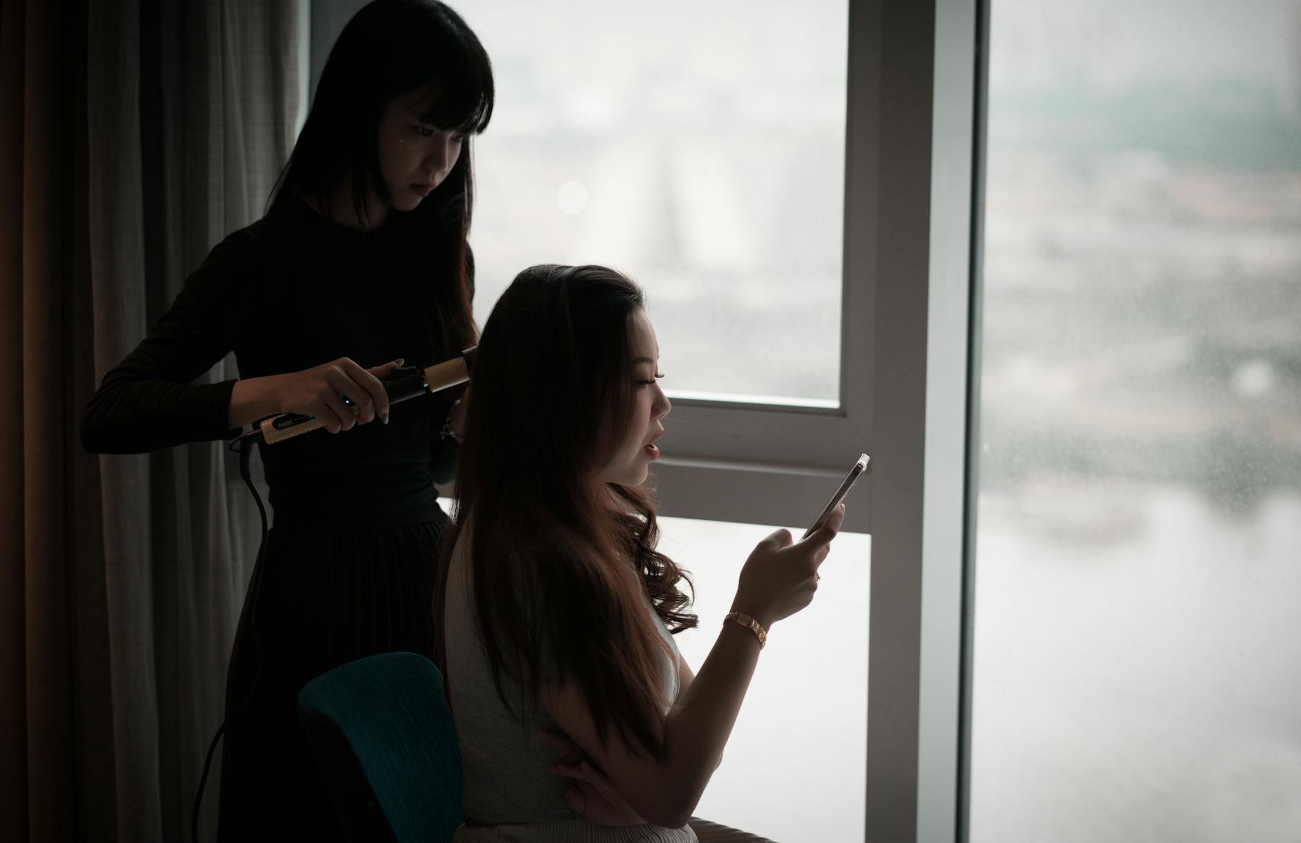 woman using hair styling tool curling long hair