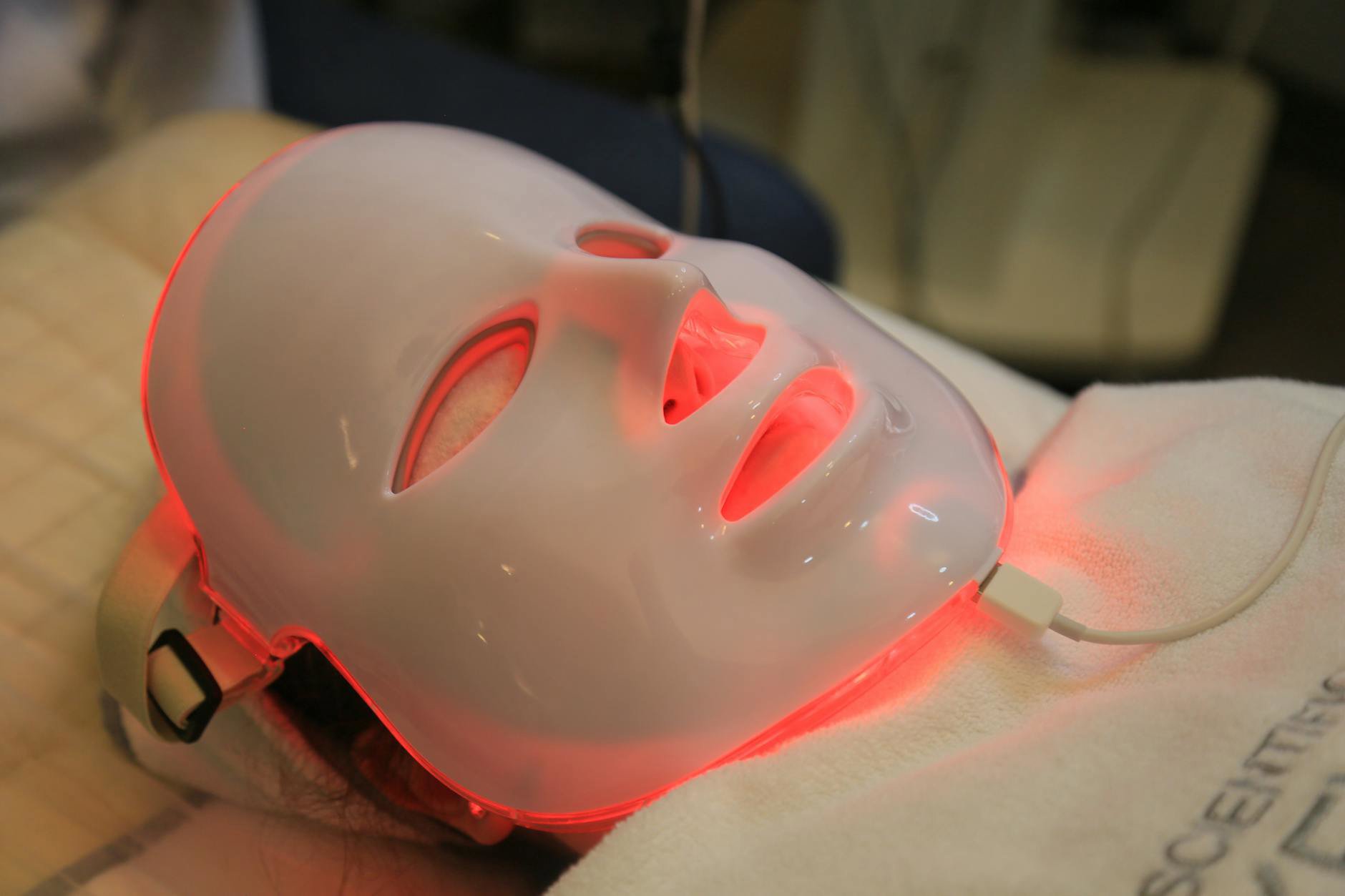 woman using LED face mask at home