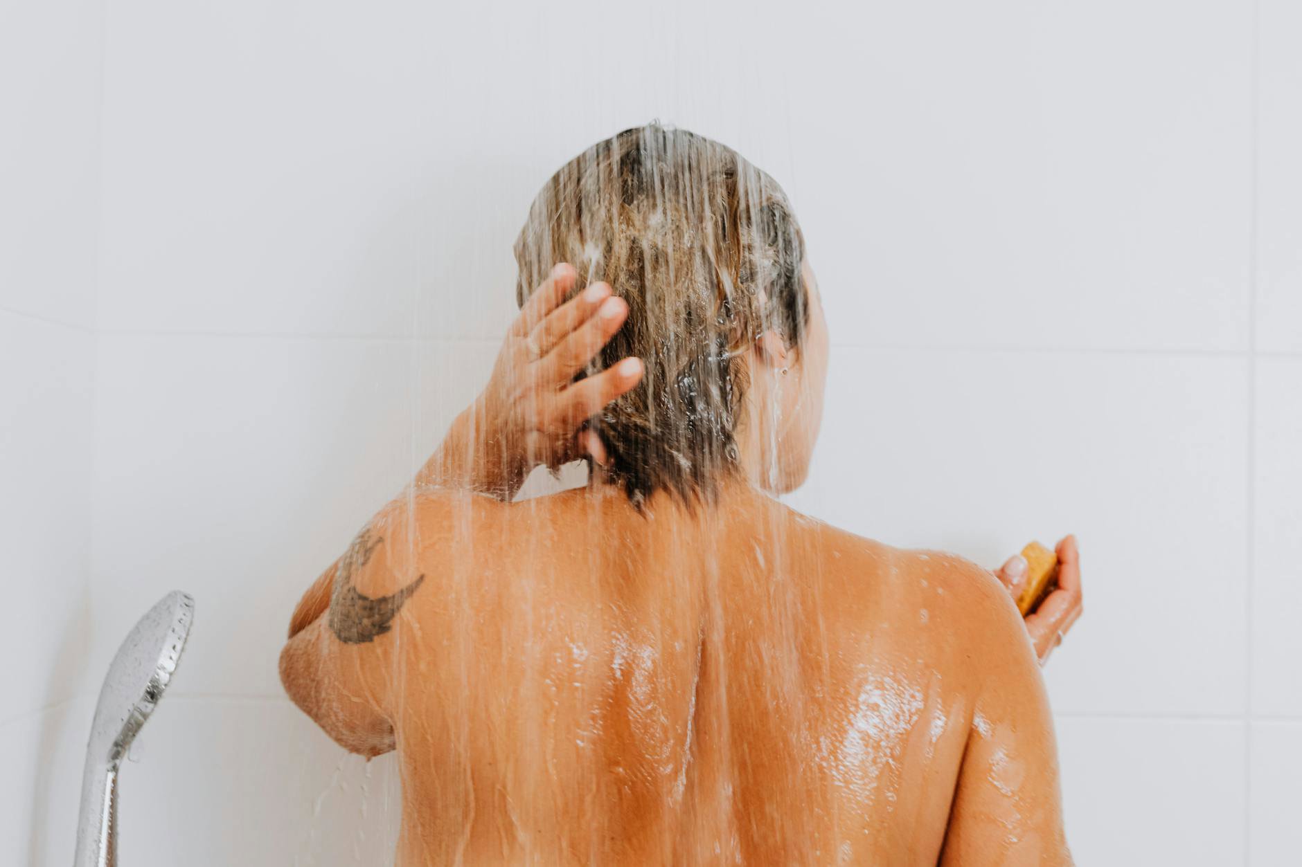 woman rinsing conditioner then washing back in shower