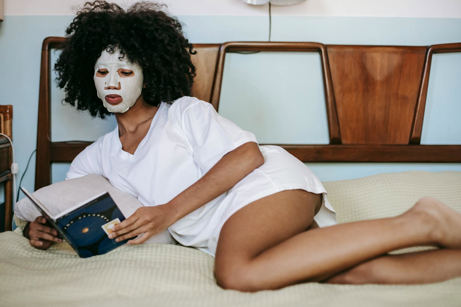 woman wearing sheet mask in bed
