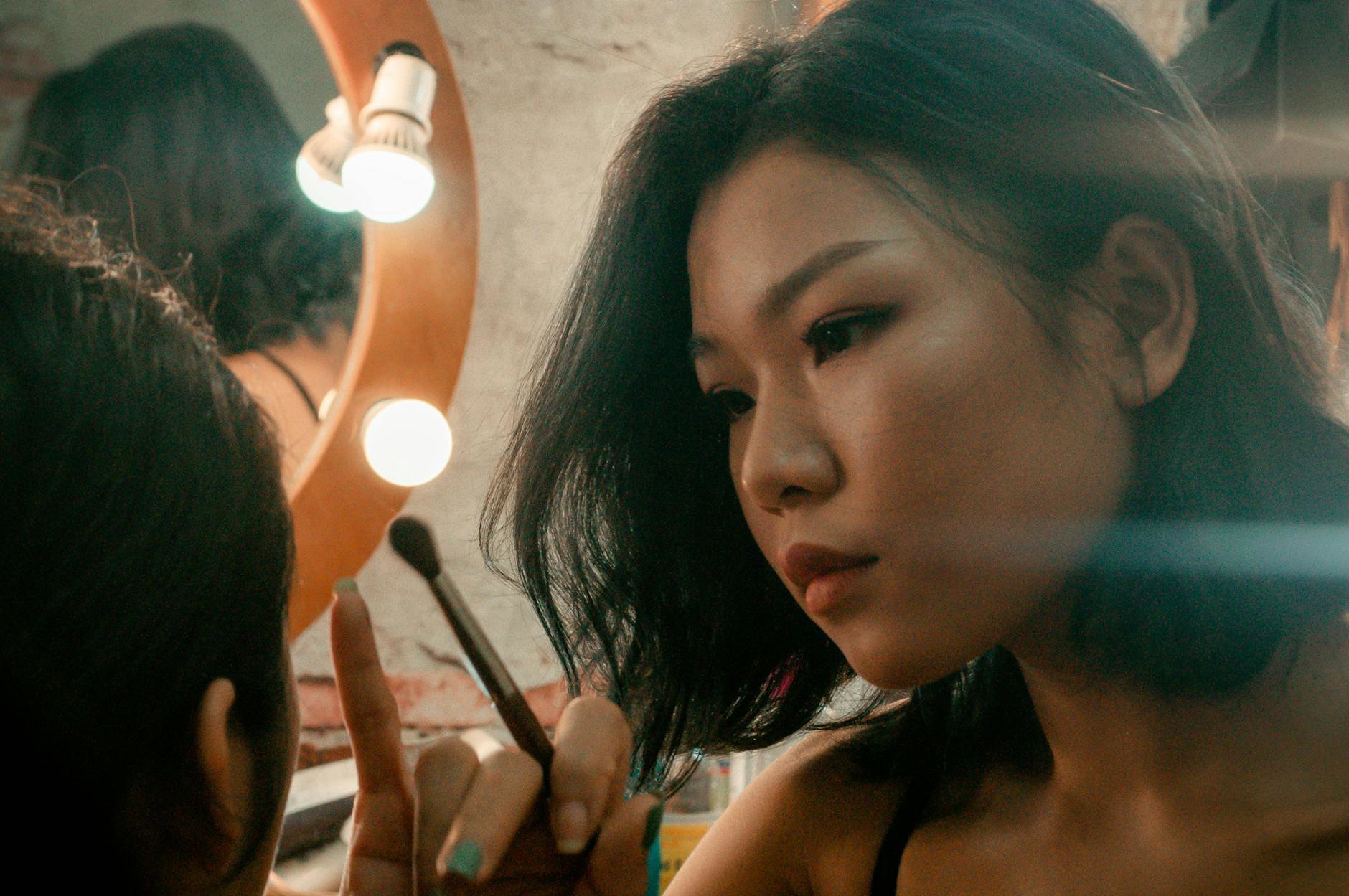 woman applying sunscreen before makeup mirror