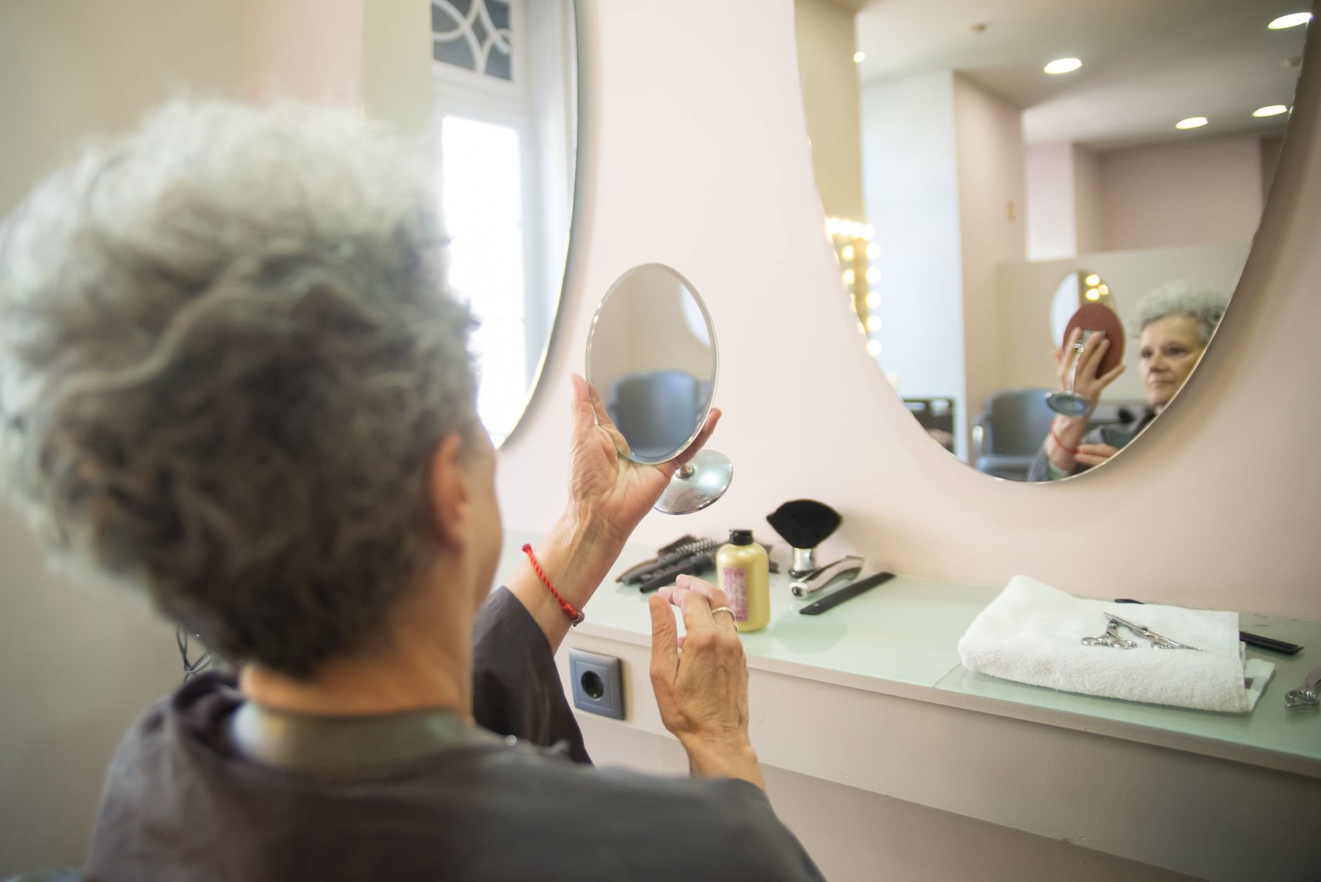 woman checking hair parting mirror