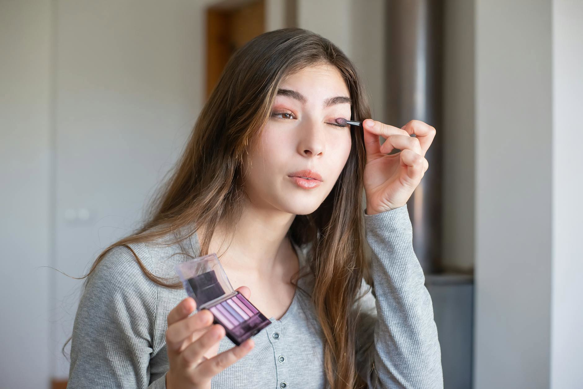woman applying eyeshadow palette bathroom mirror