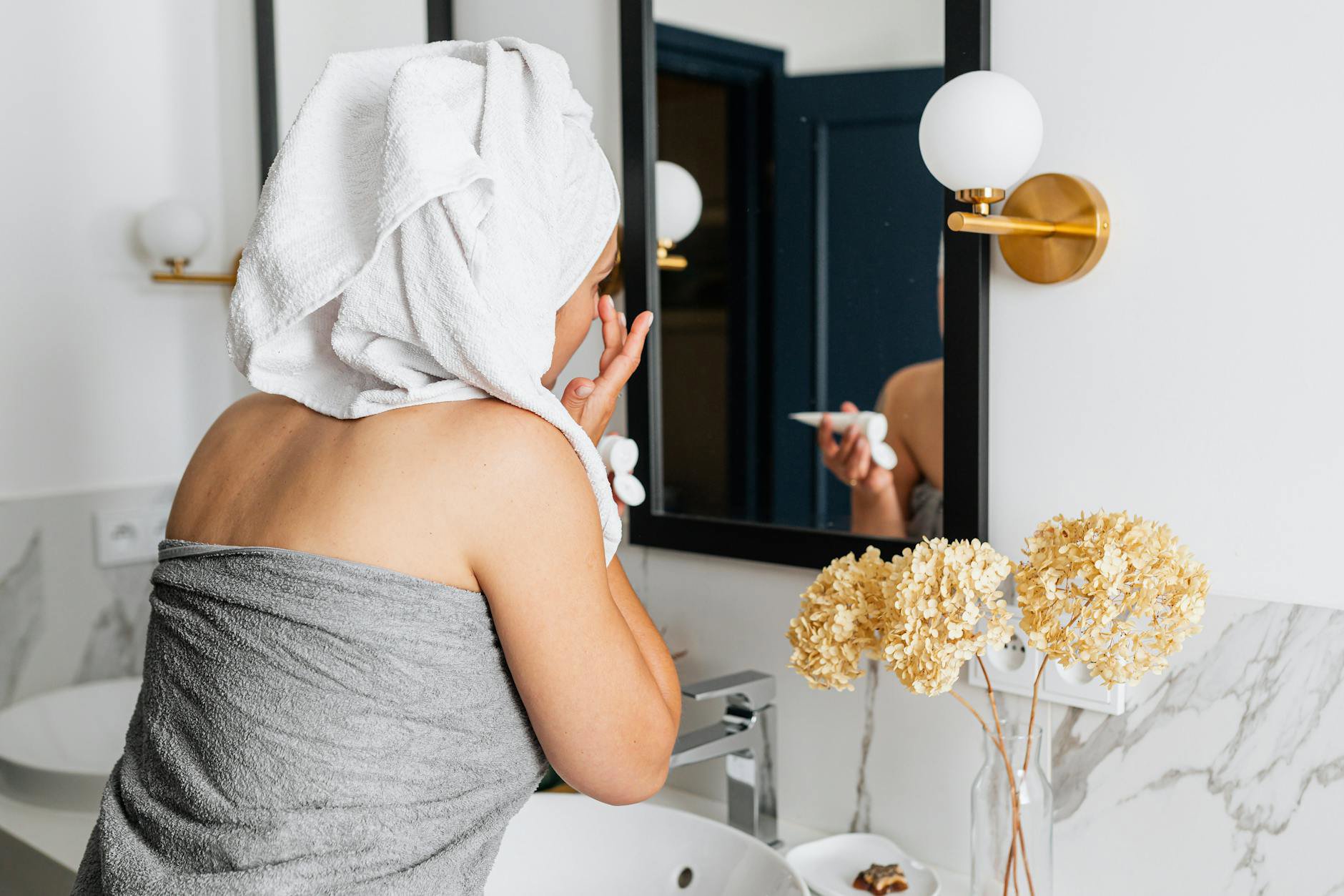 woman applying body cream after shower
