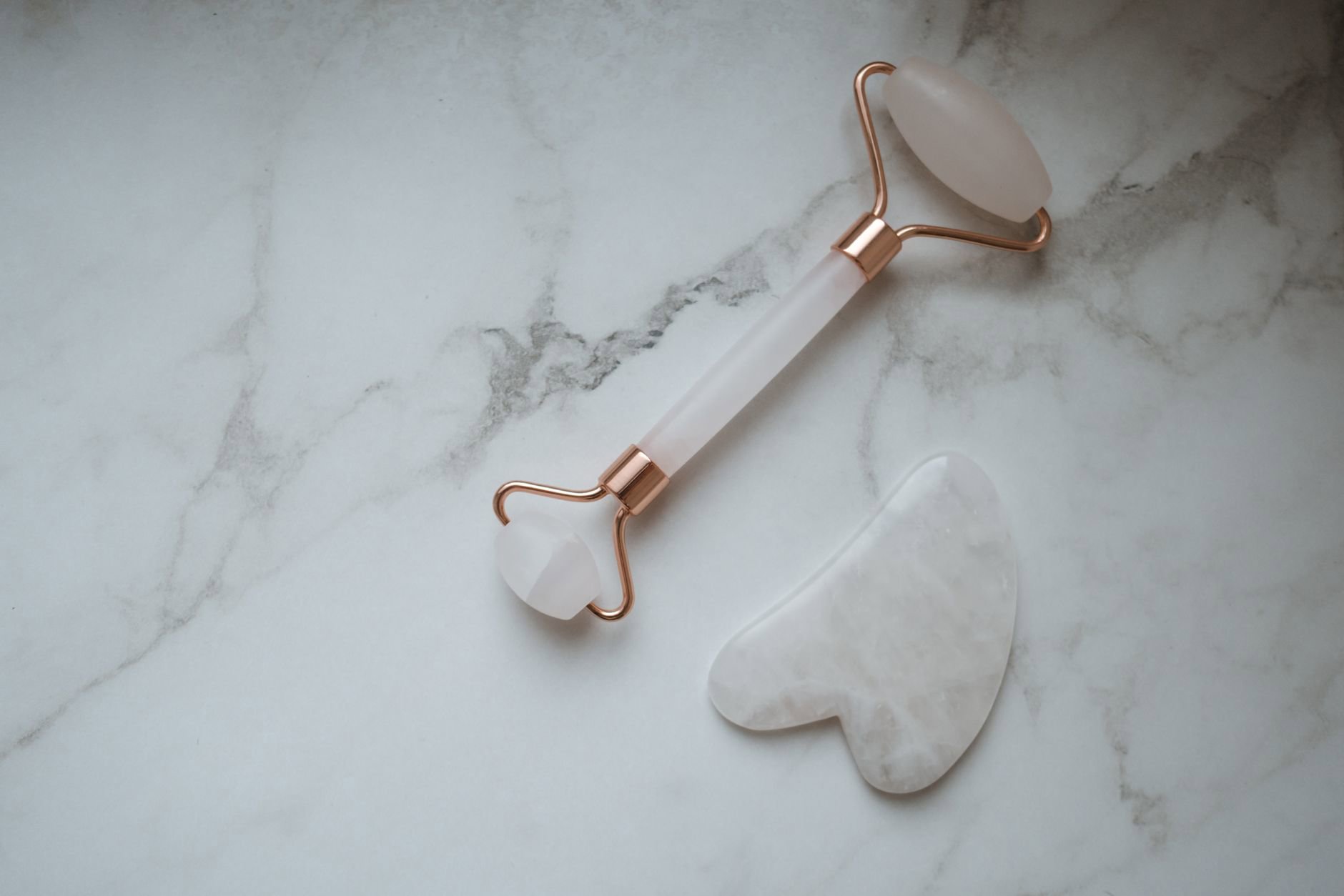Rose quartz gua sha tool on bathroom counter
