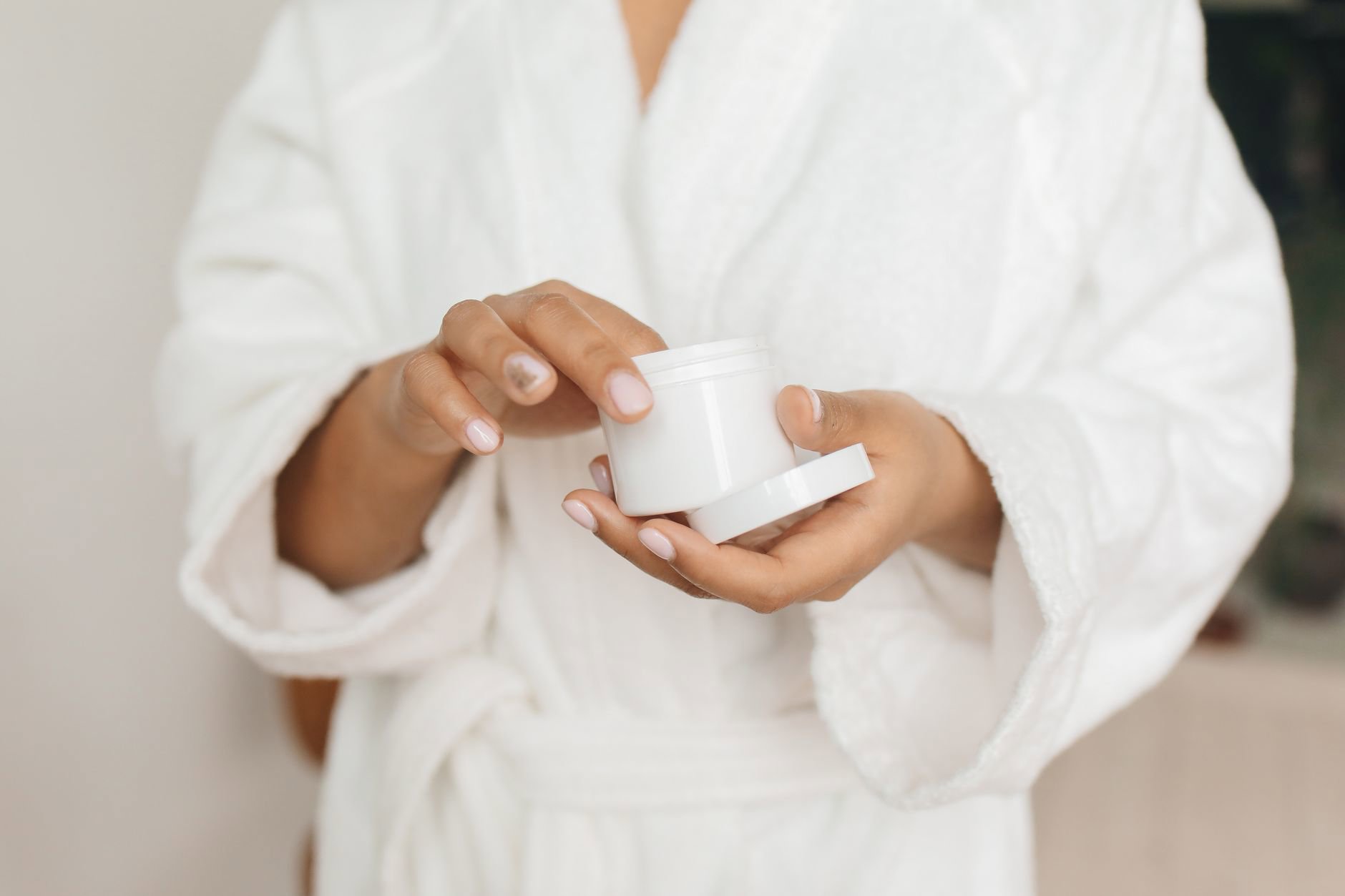 woman holding skincare jar bathroom shelf
