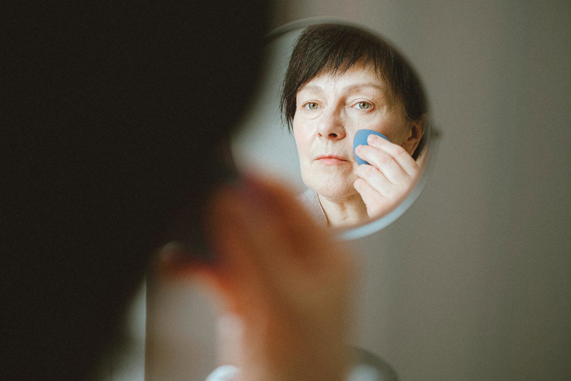 woman applying foundation with makeup sponge close up