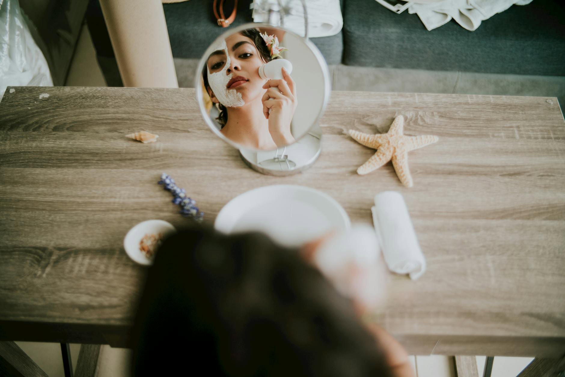 woman applying dry shampoo to roots mirror