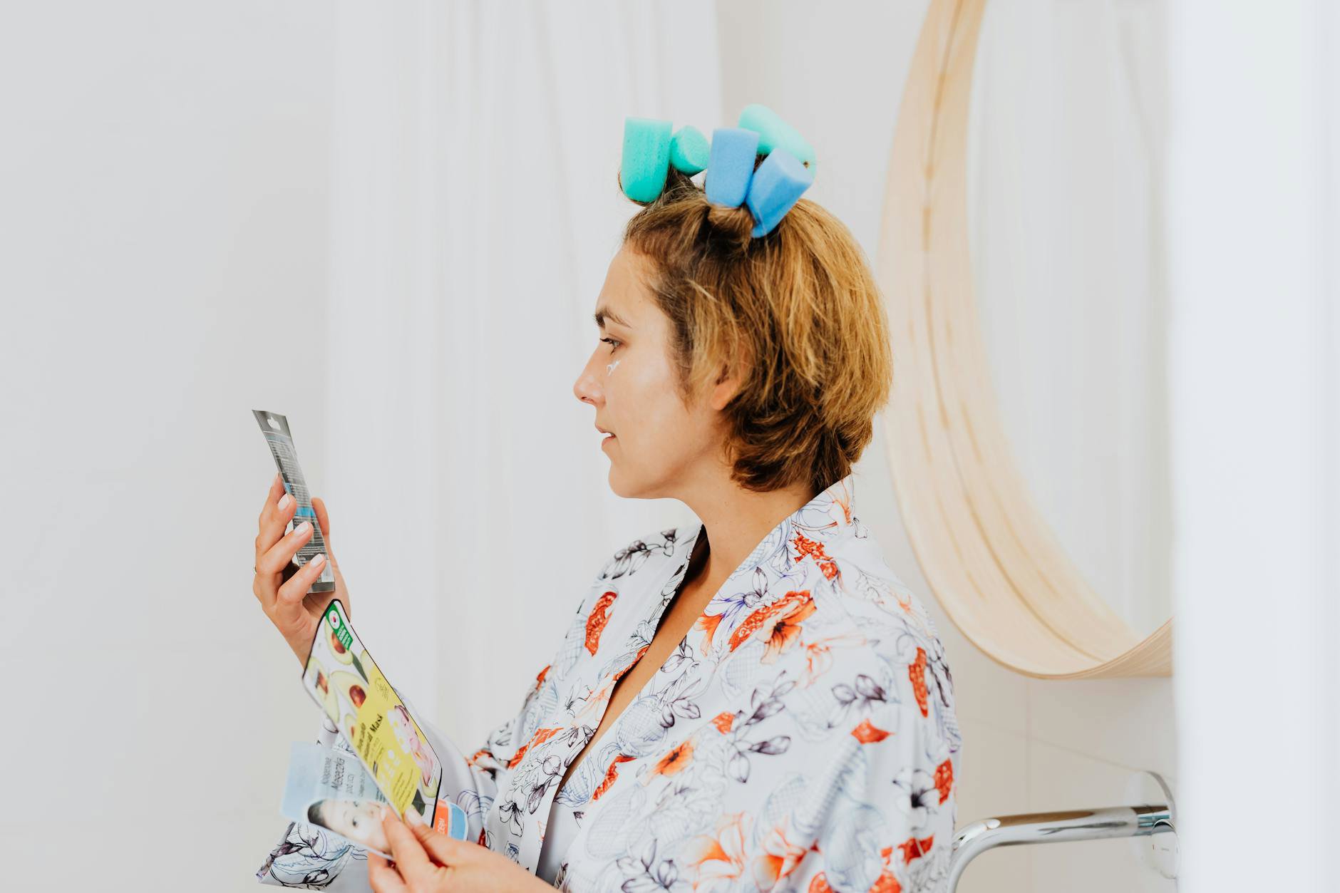 woman reading skincare label in bathroom mirror