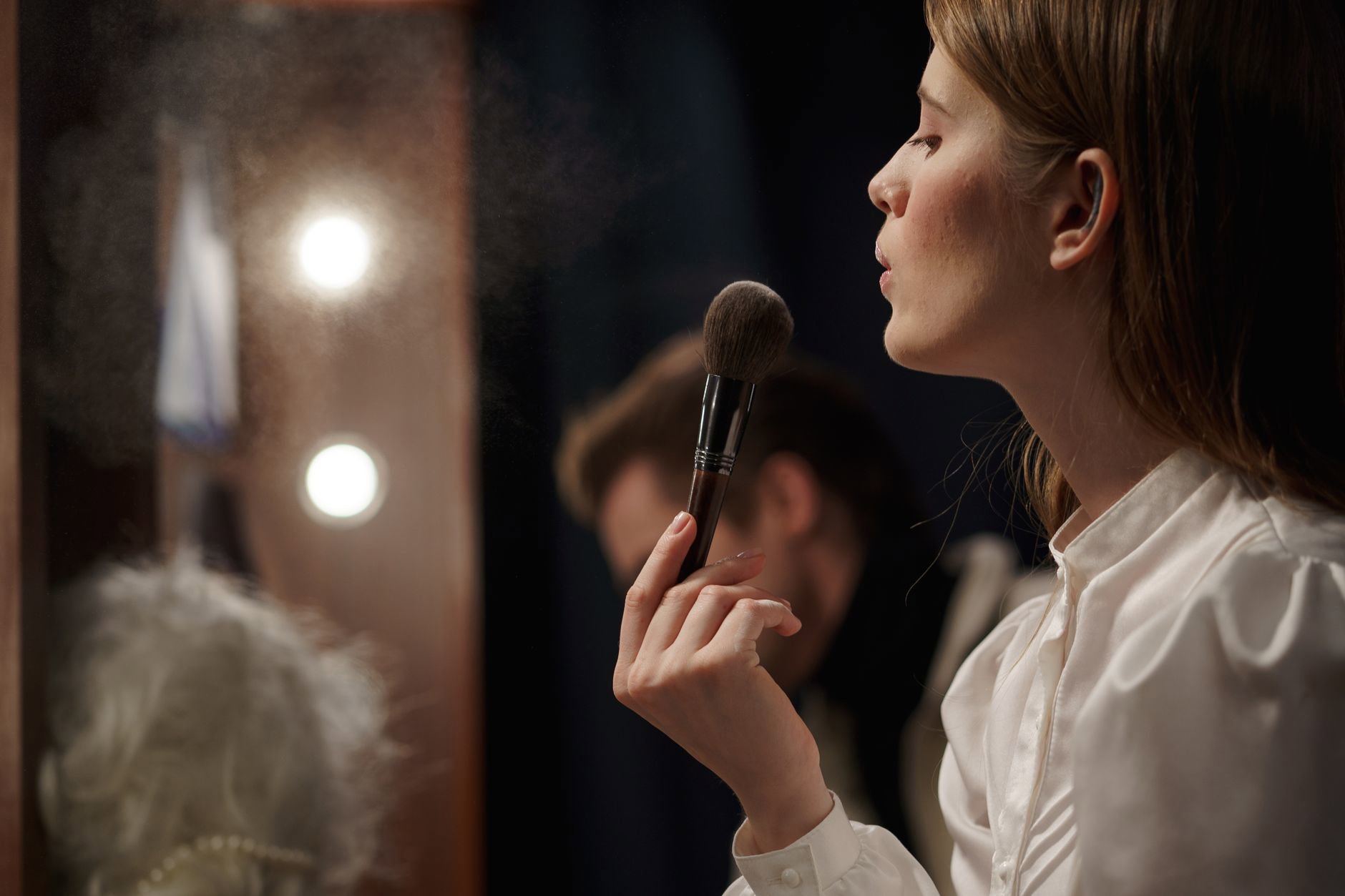 woman applying hair volumizing powder at crown mirror