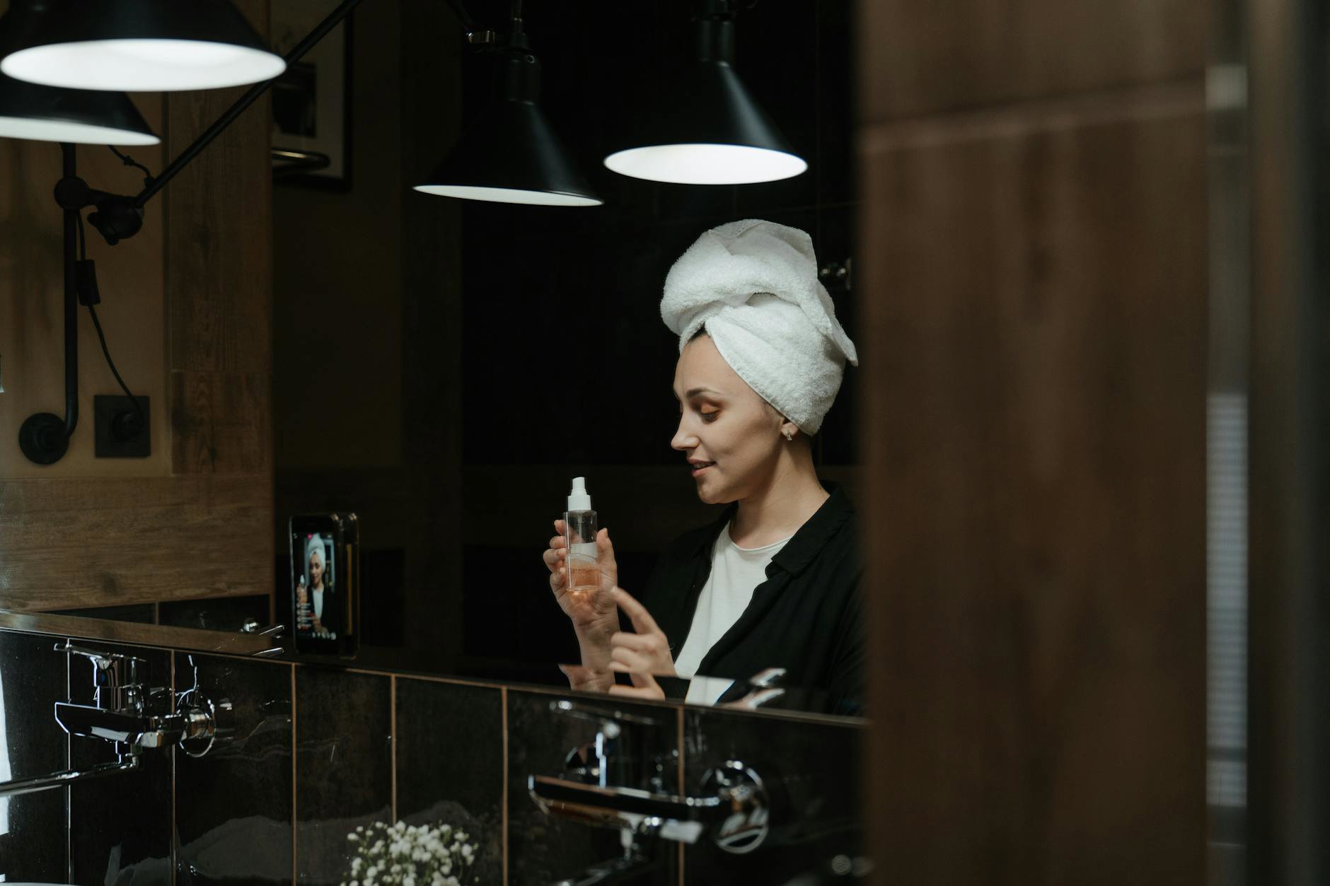 woman applying setting spray in bathroom mirror