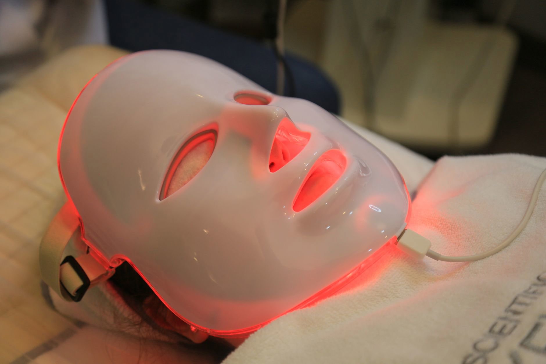 woman using LED face mask at home