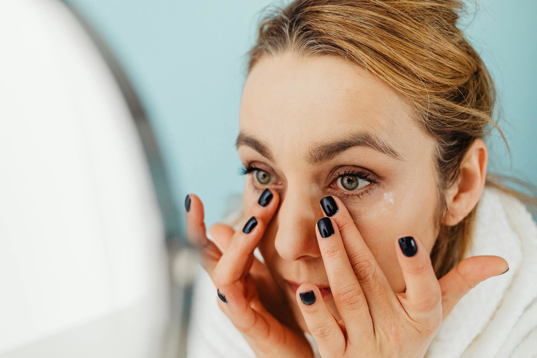woman applying eye cream tapping technique mirror