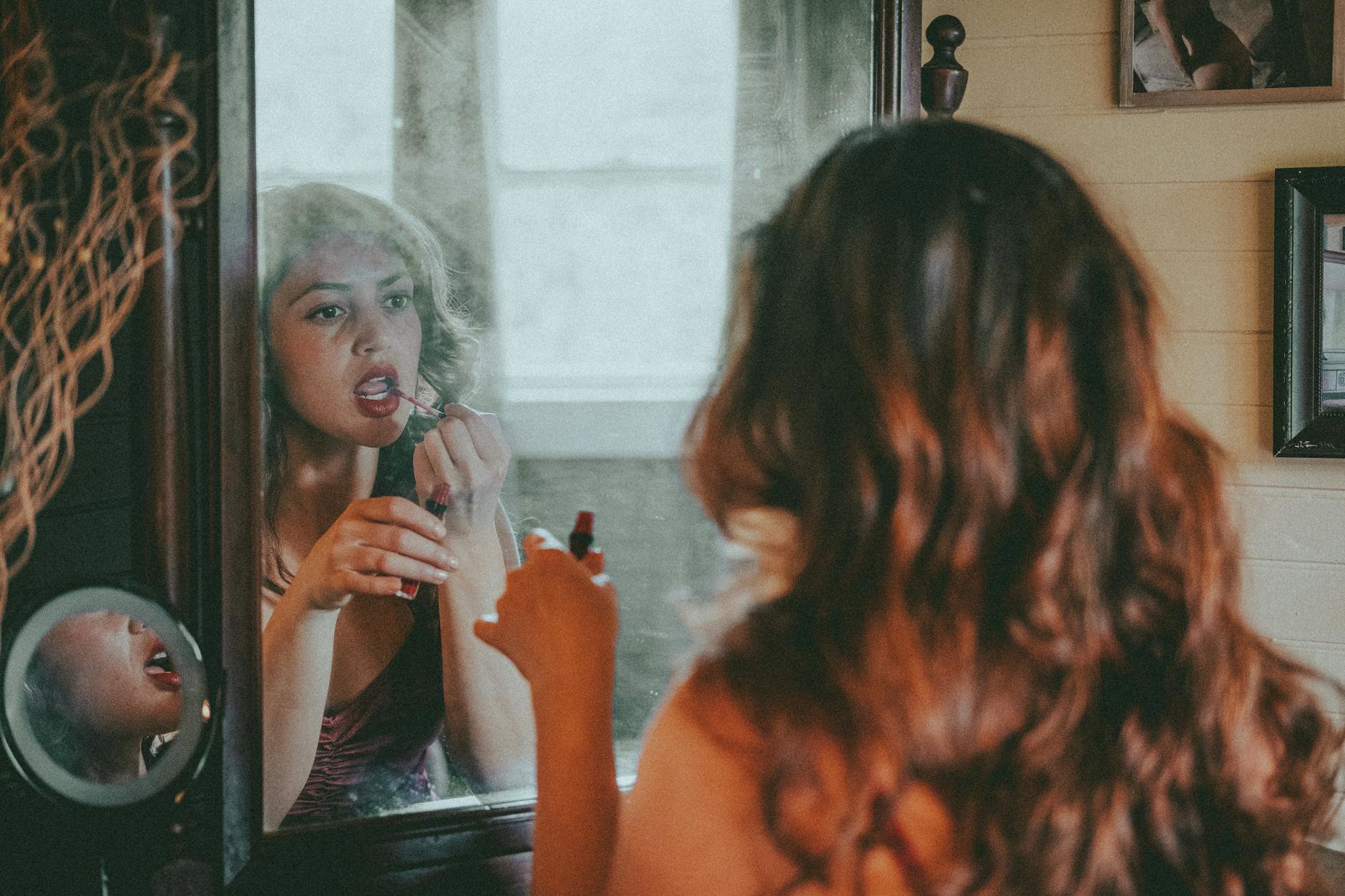 woman applying lip gloss mirror minimal makeup