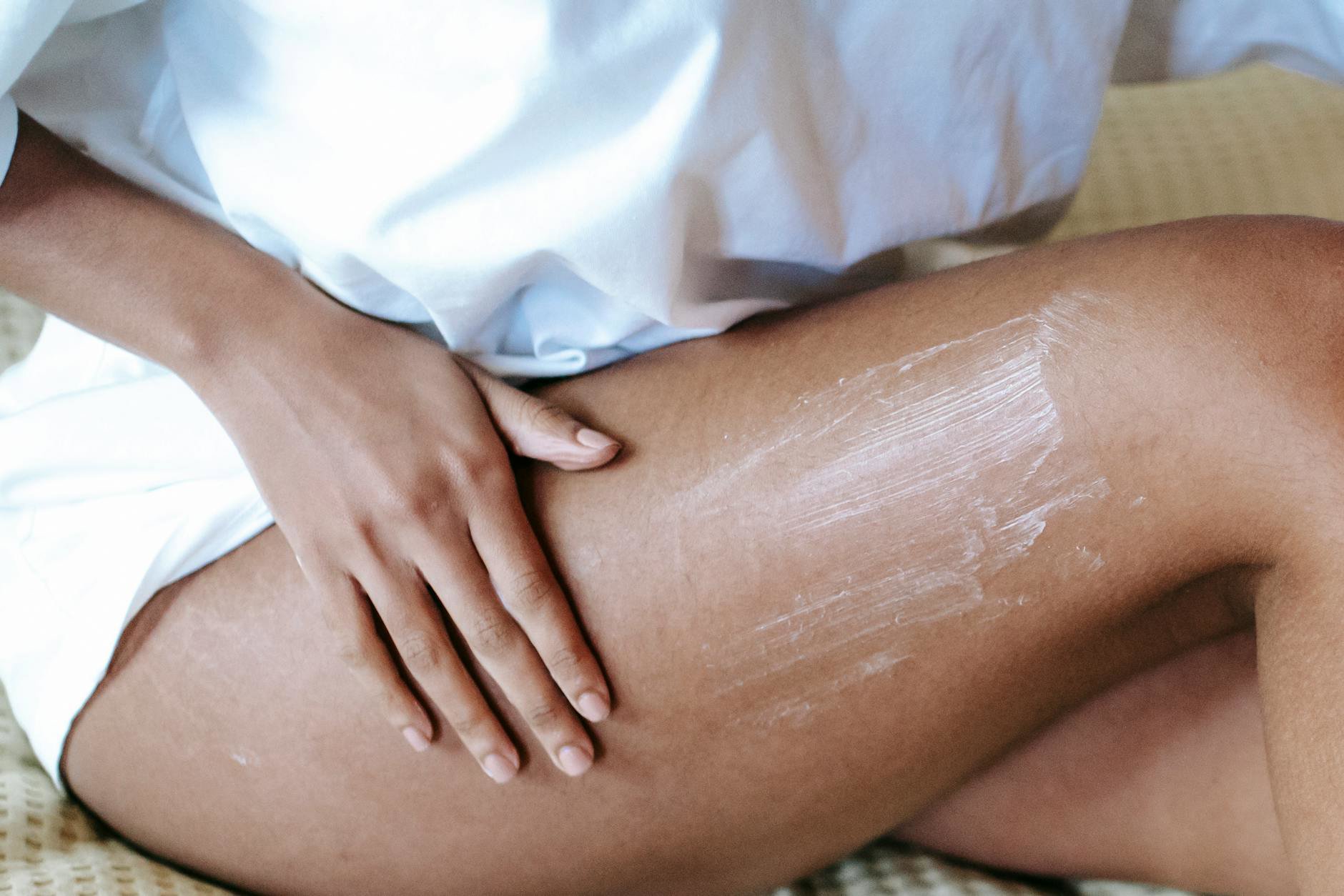 woman applying body lotion after shower