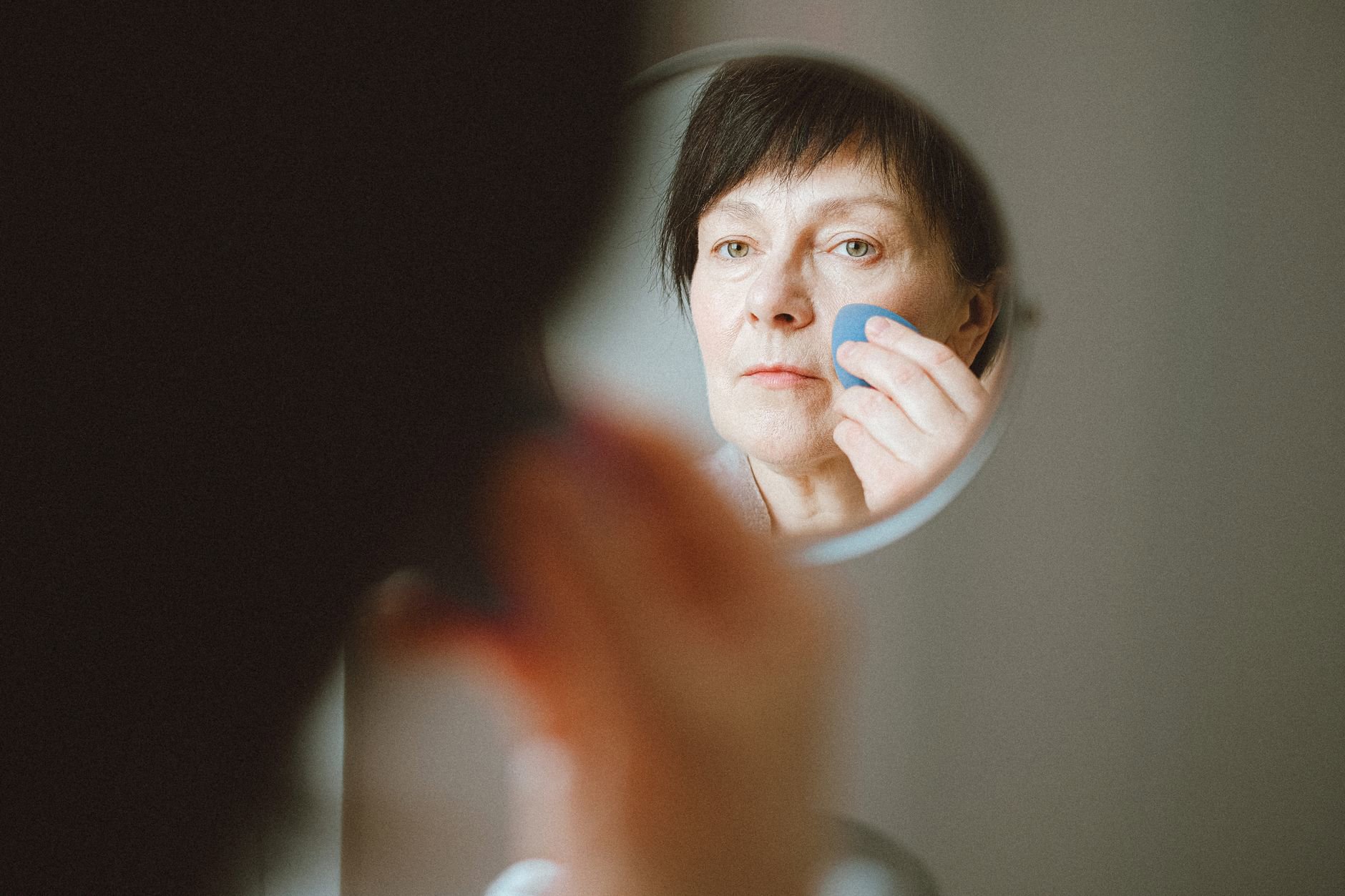 woman applying soft focus foundation with sponge mirror