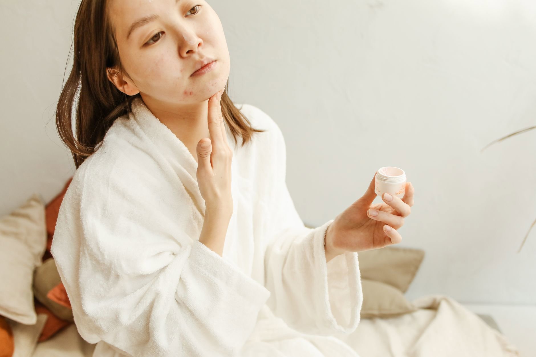 woman applying moisturizer after acne serum