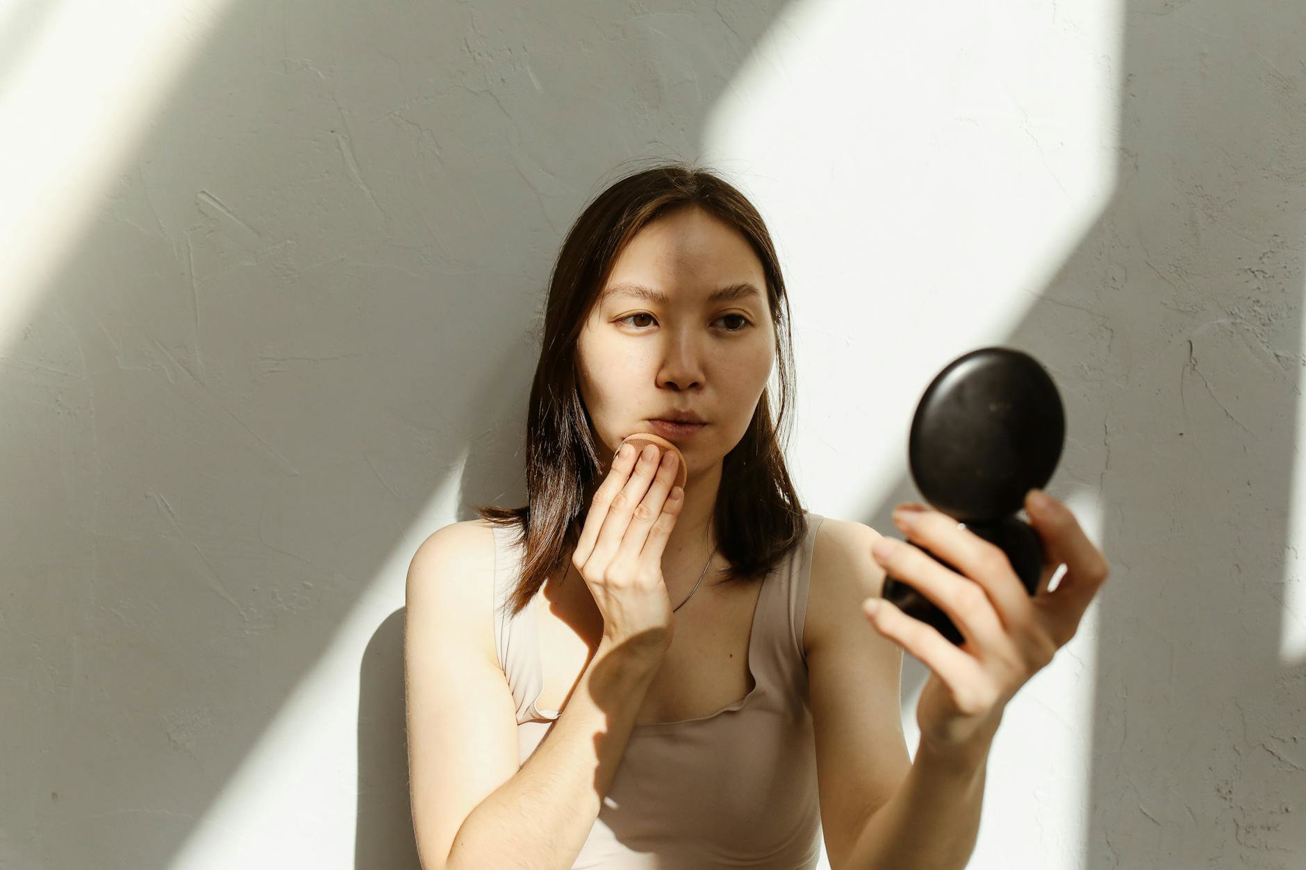 woman reapplying sunscreen over makeup with stick