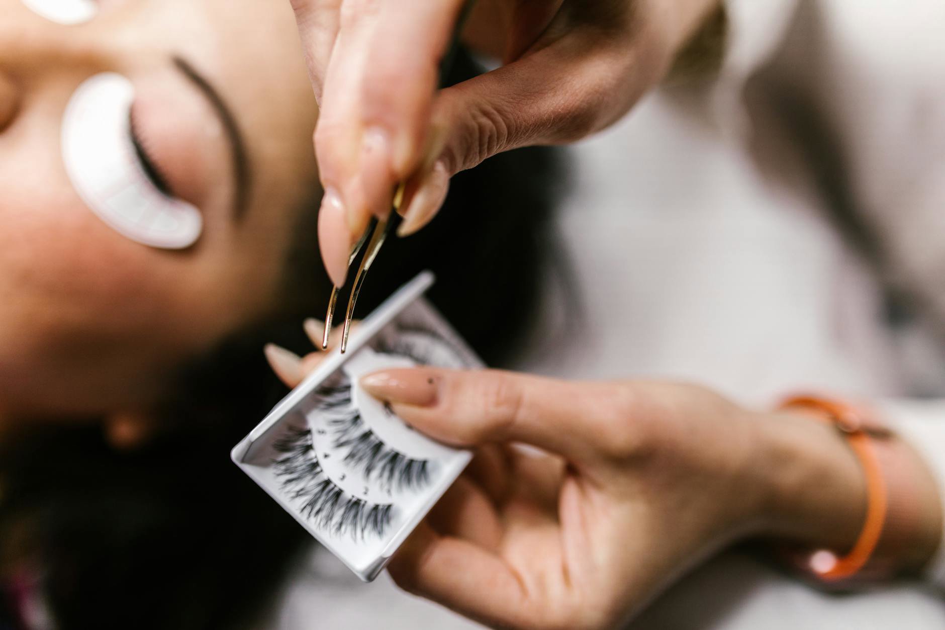 woman removing false lashes bathroom mirror