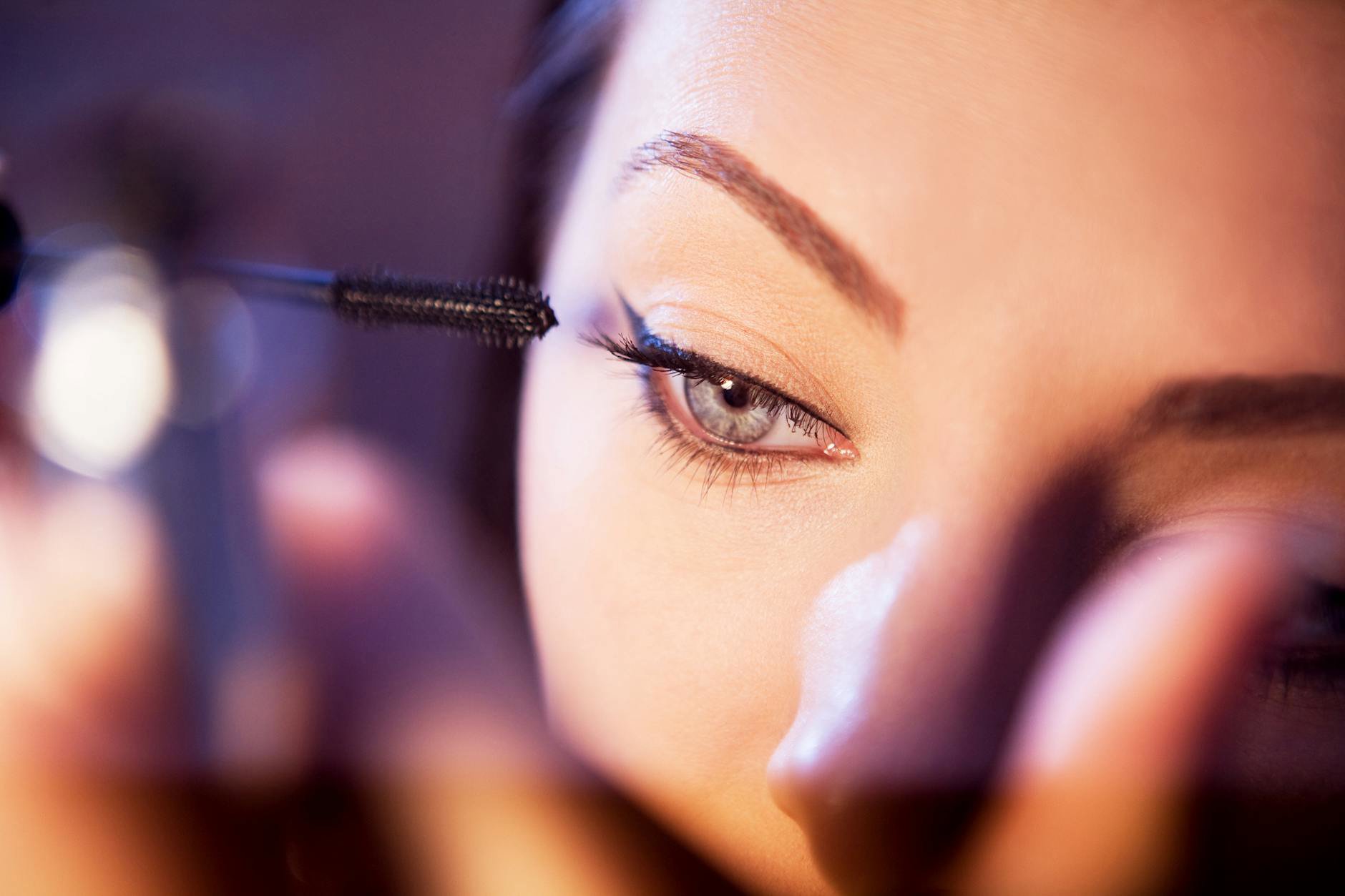 close up woman applying mascara wand