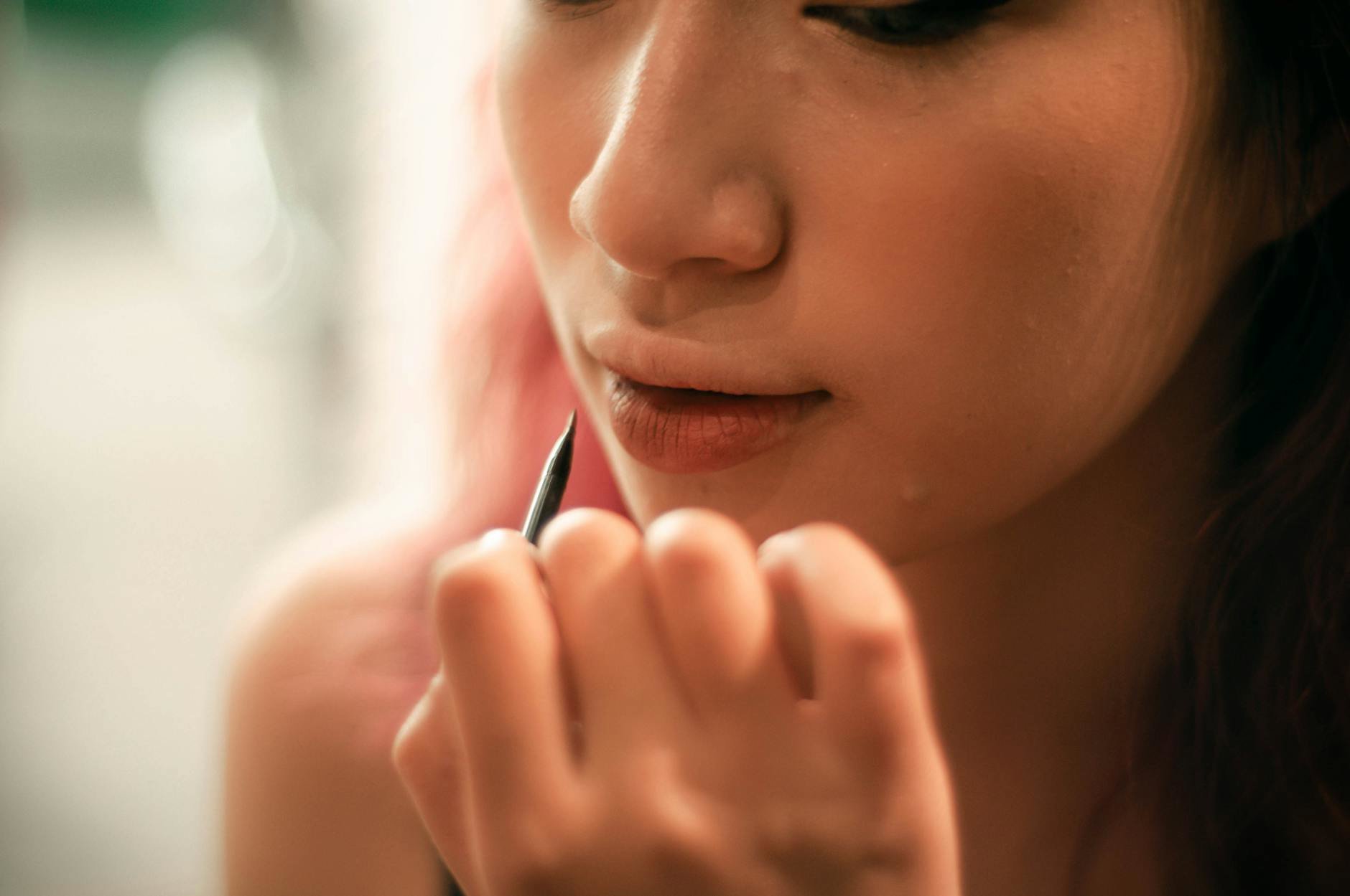 woman applying pencil eyeliner close up