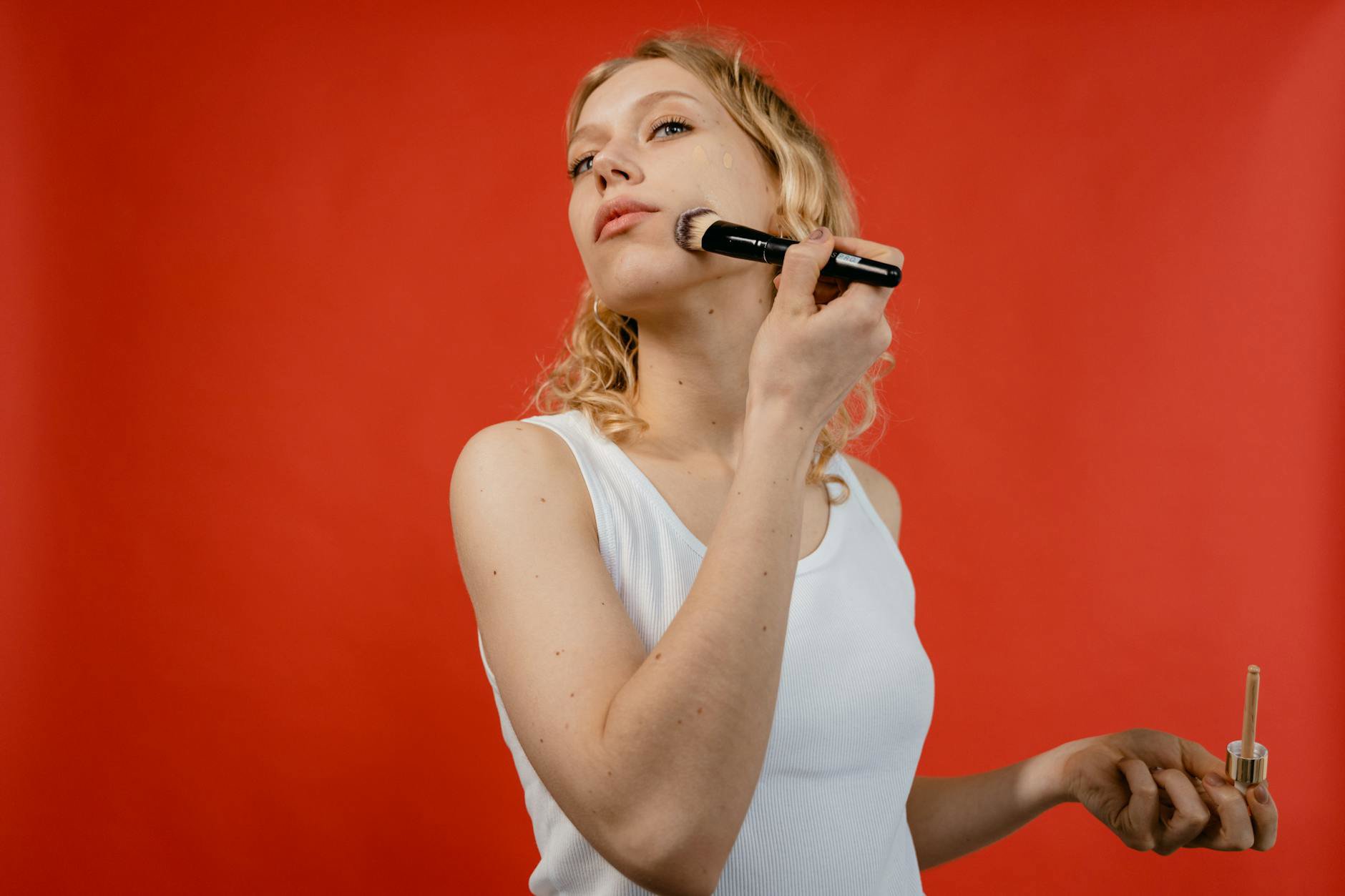 woman using small brush to conceal blemish