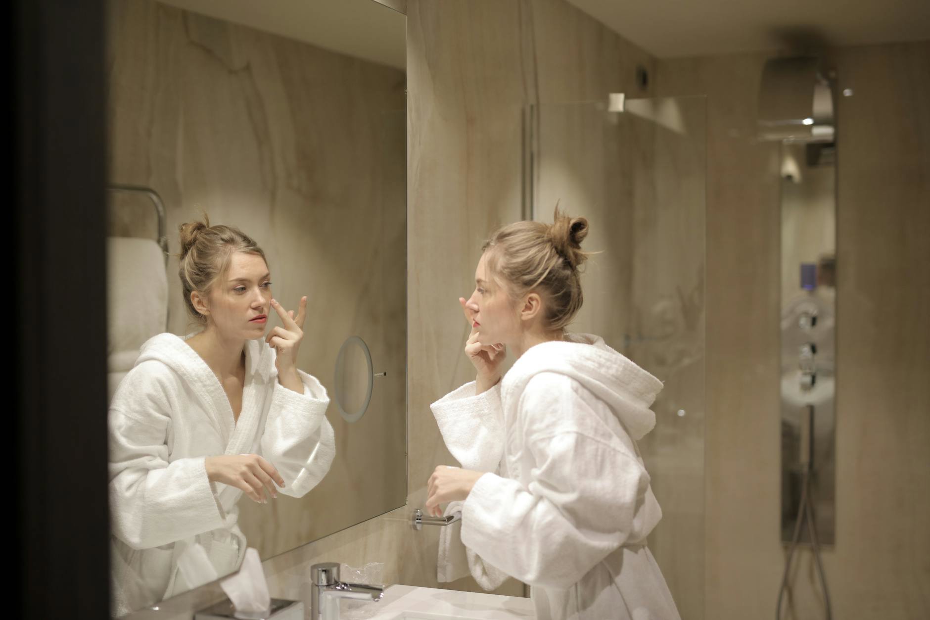 woman applying night cream bathroom mirror