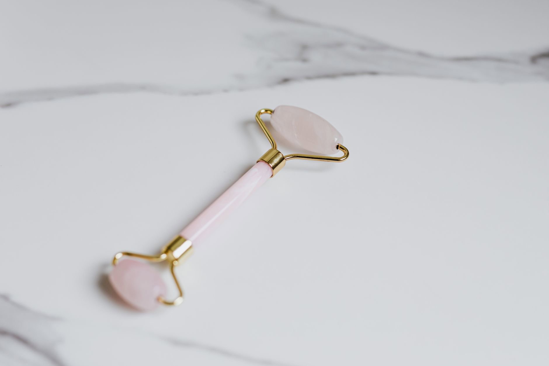 rose quartz facial roller on marble counter
