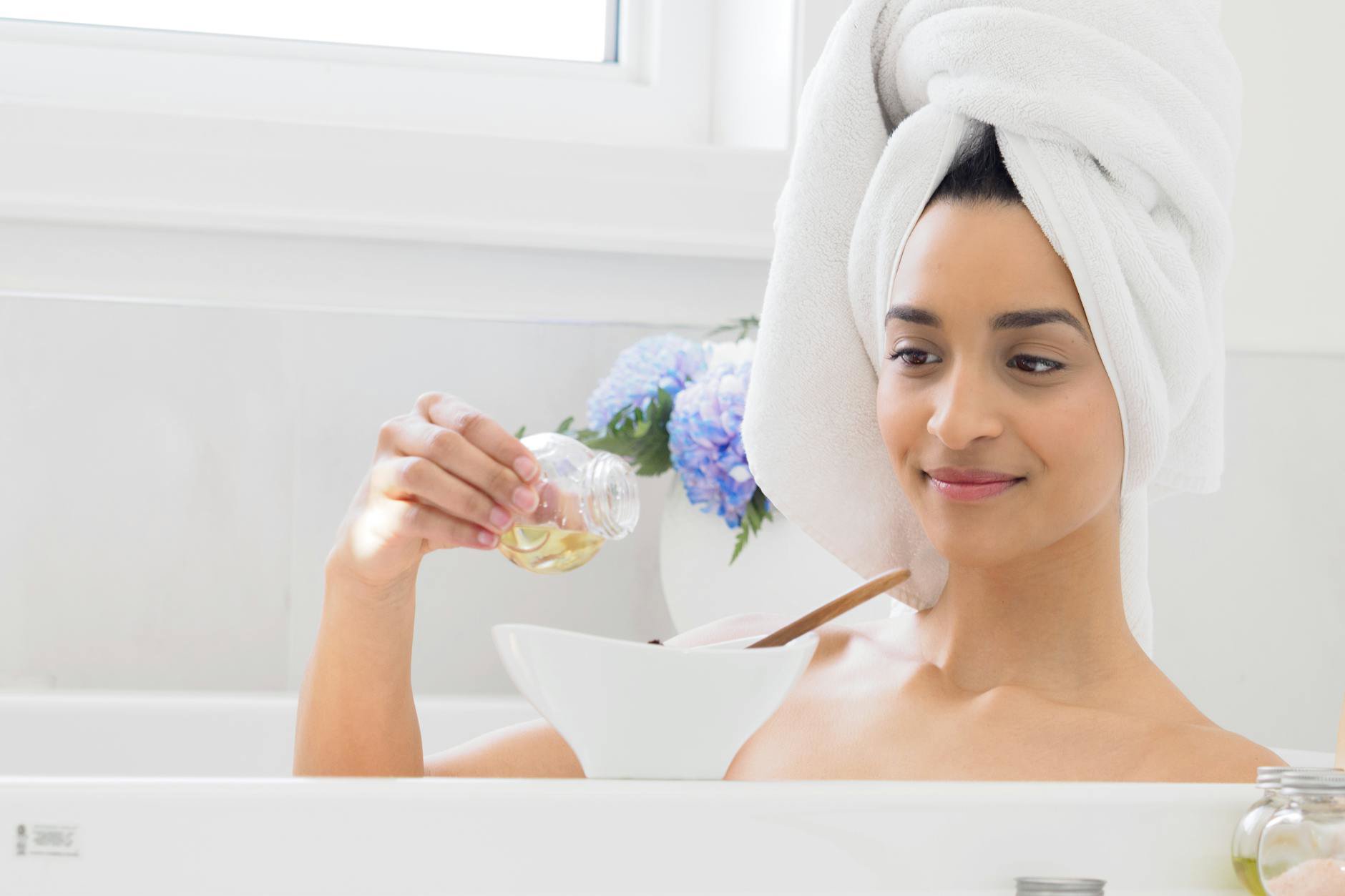measuring bath oil into small cup by bathtub