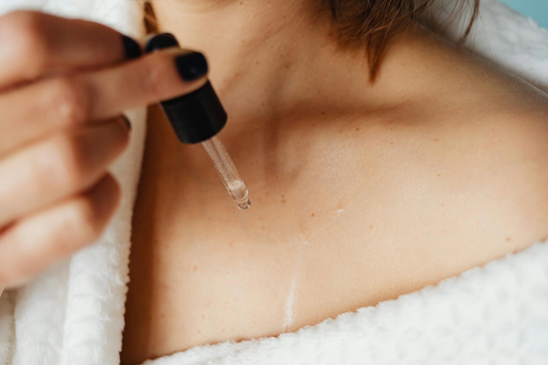 woman applying body oil on damp skin after shower