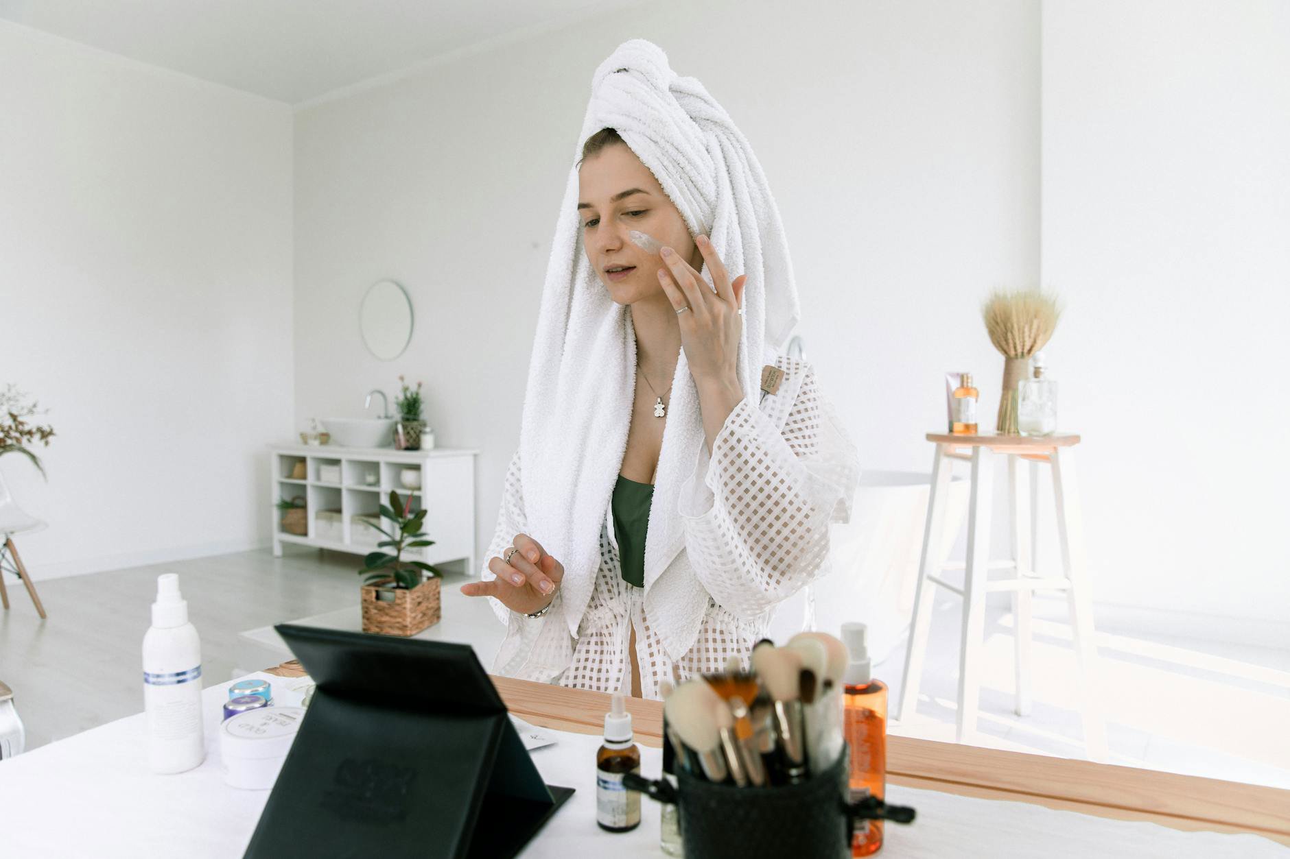 woman applying face serum morning bathroom mirror