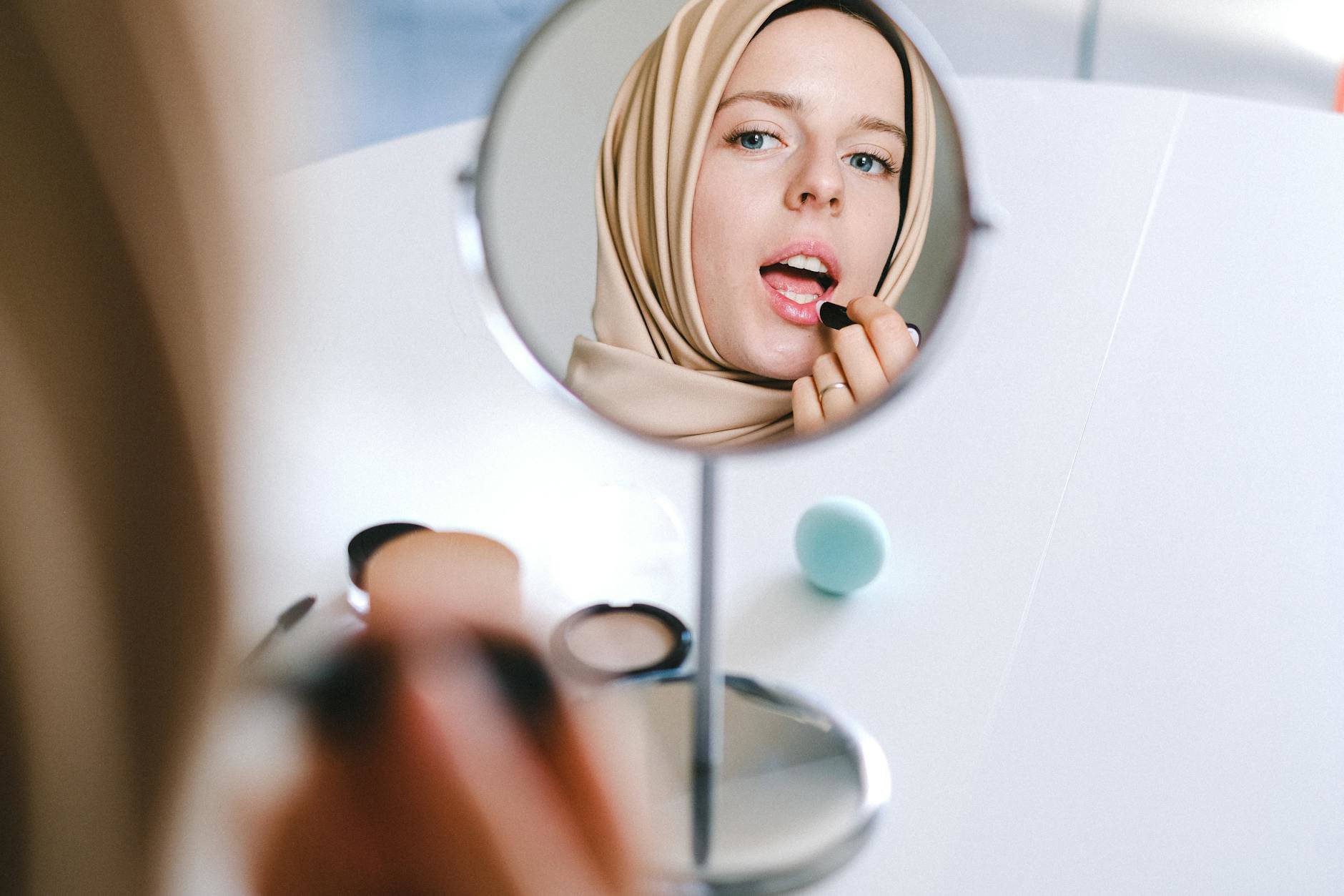 woman applying primer makeup mirror