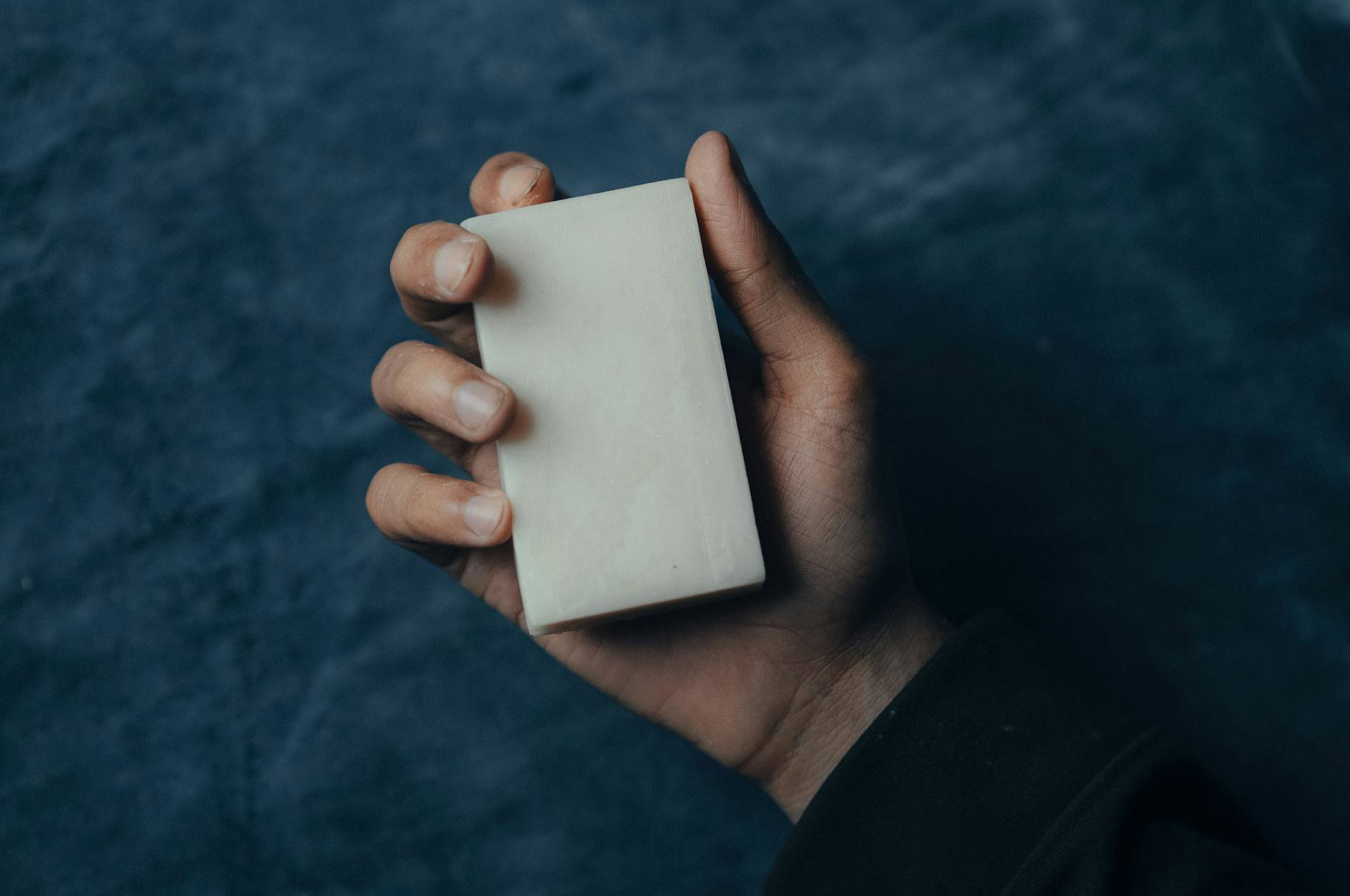 person holding bar soap and body wash comparison