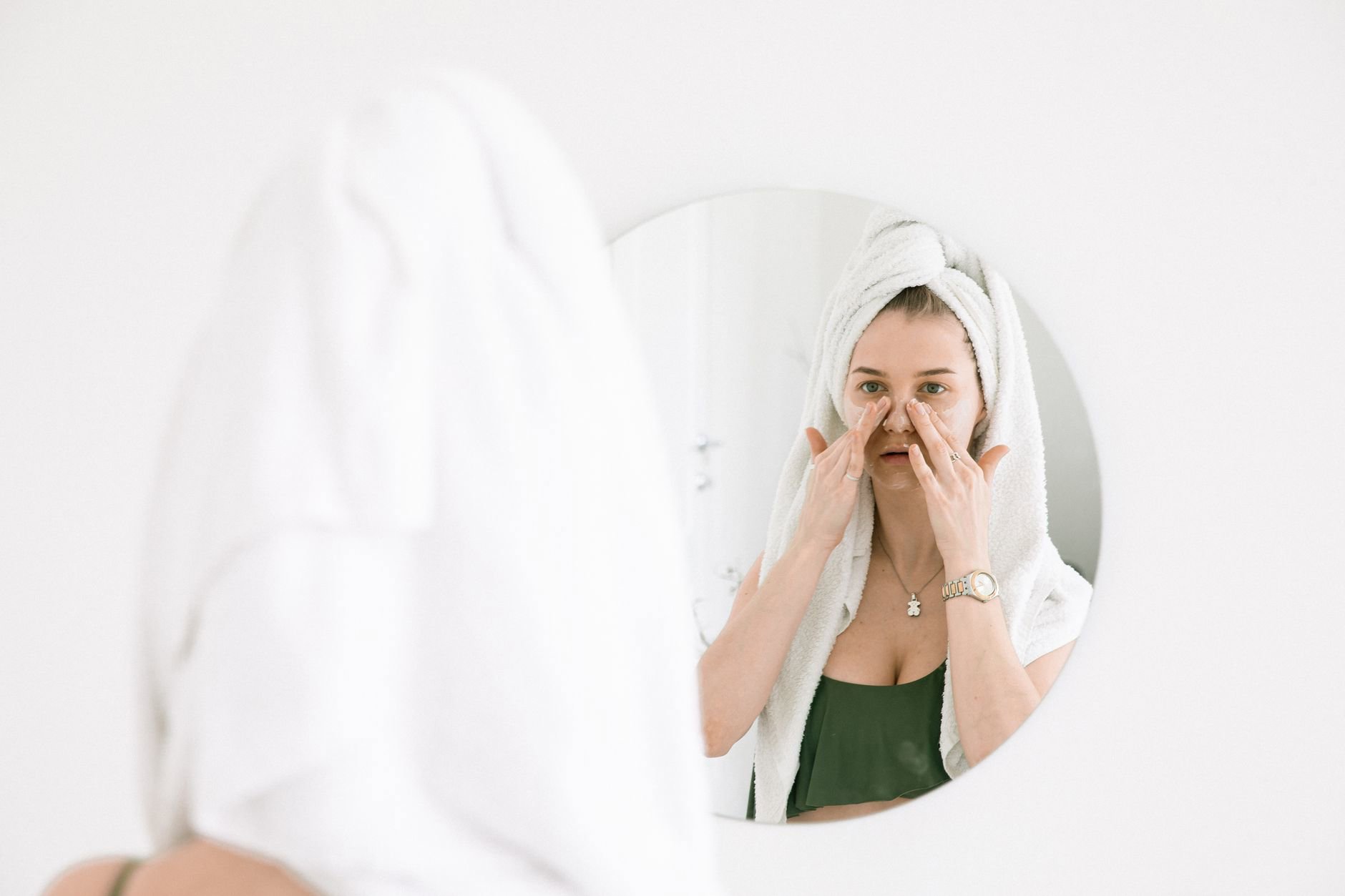 woman applying gel moisturiser in bathroom mirror