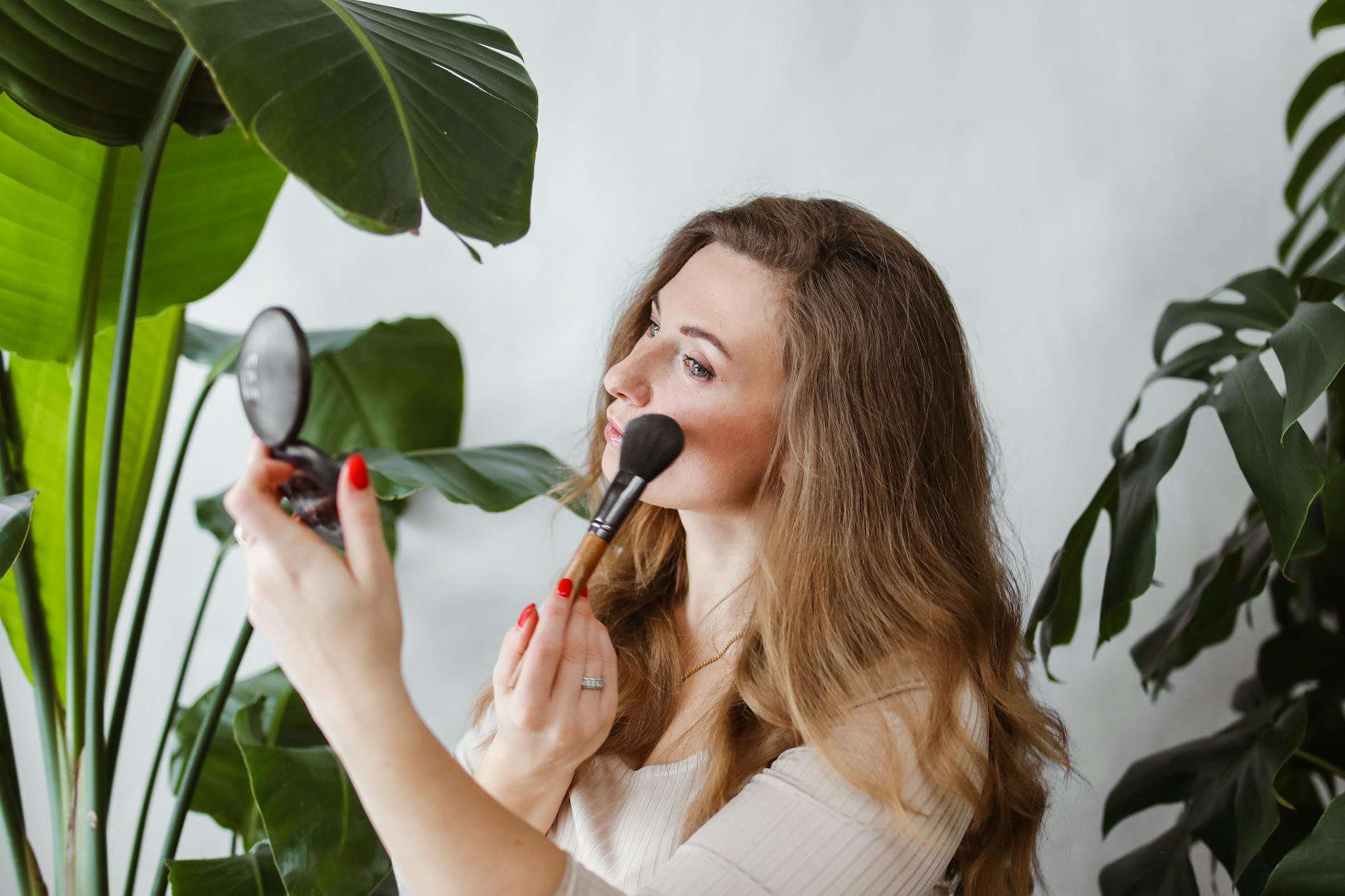 woman applying pink blush cream cheek close up