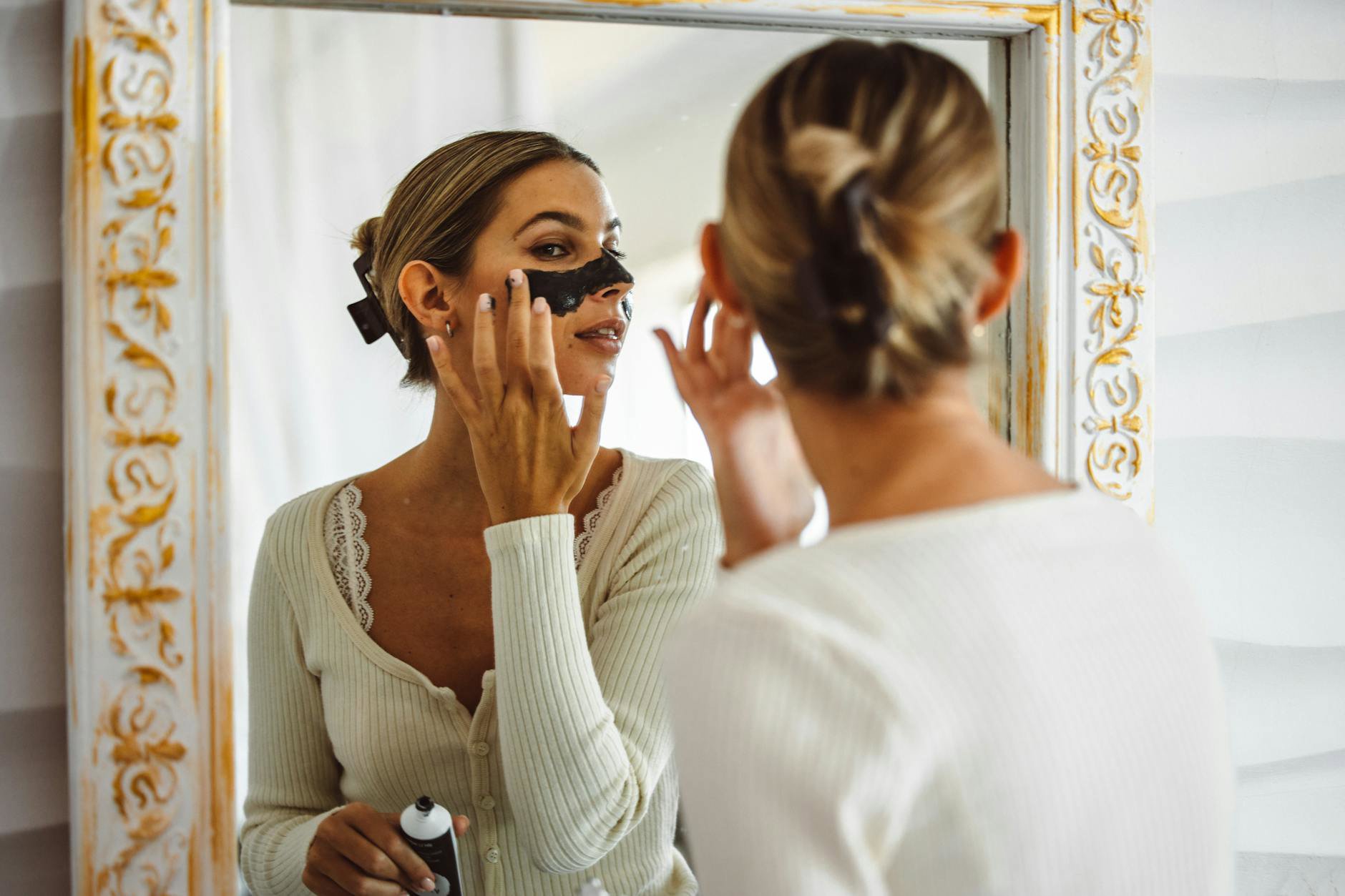 woman applying face mask bathroom mirror