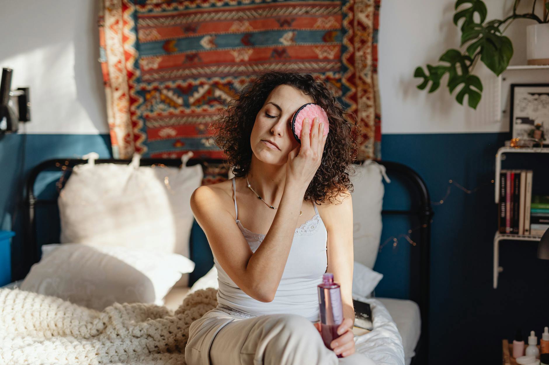 woman removing makeup with cotton pad bathroom mirror