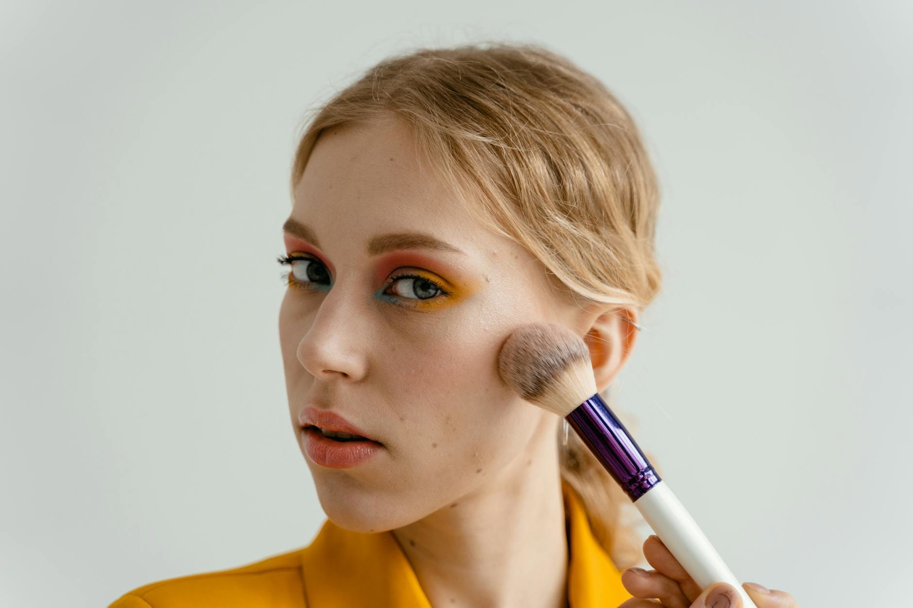 woman applying eyeshadow with flat brush close up