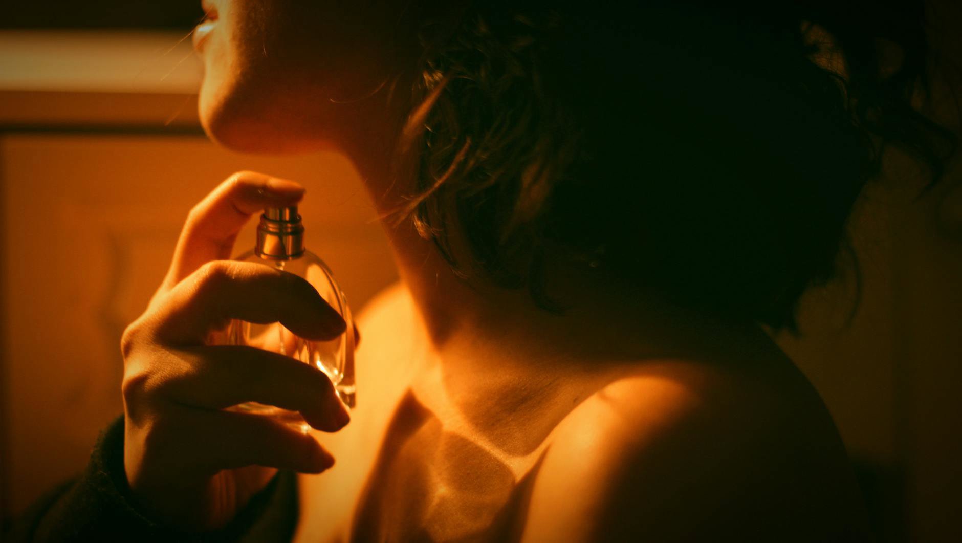 woman applying perfume on neck evening ready