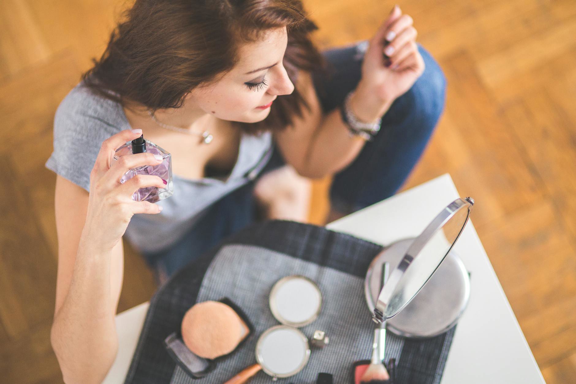 woman spraying perfume on scarf in mirror
