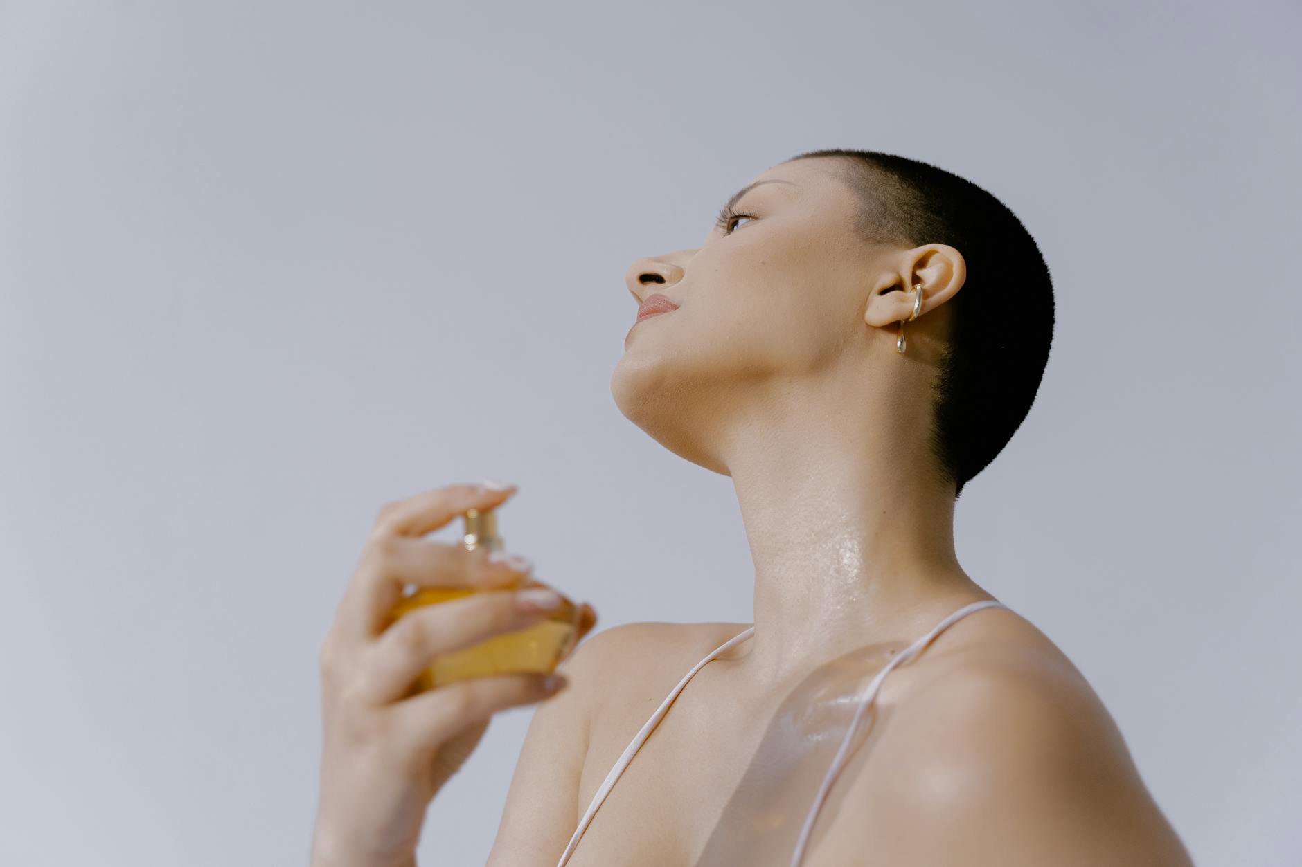 woman applying perfume on neck close up