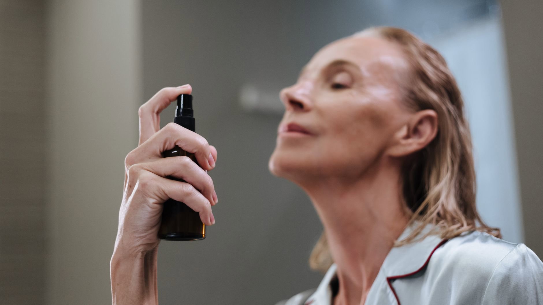 woman spraying face mist indoors